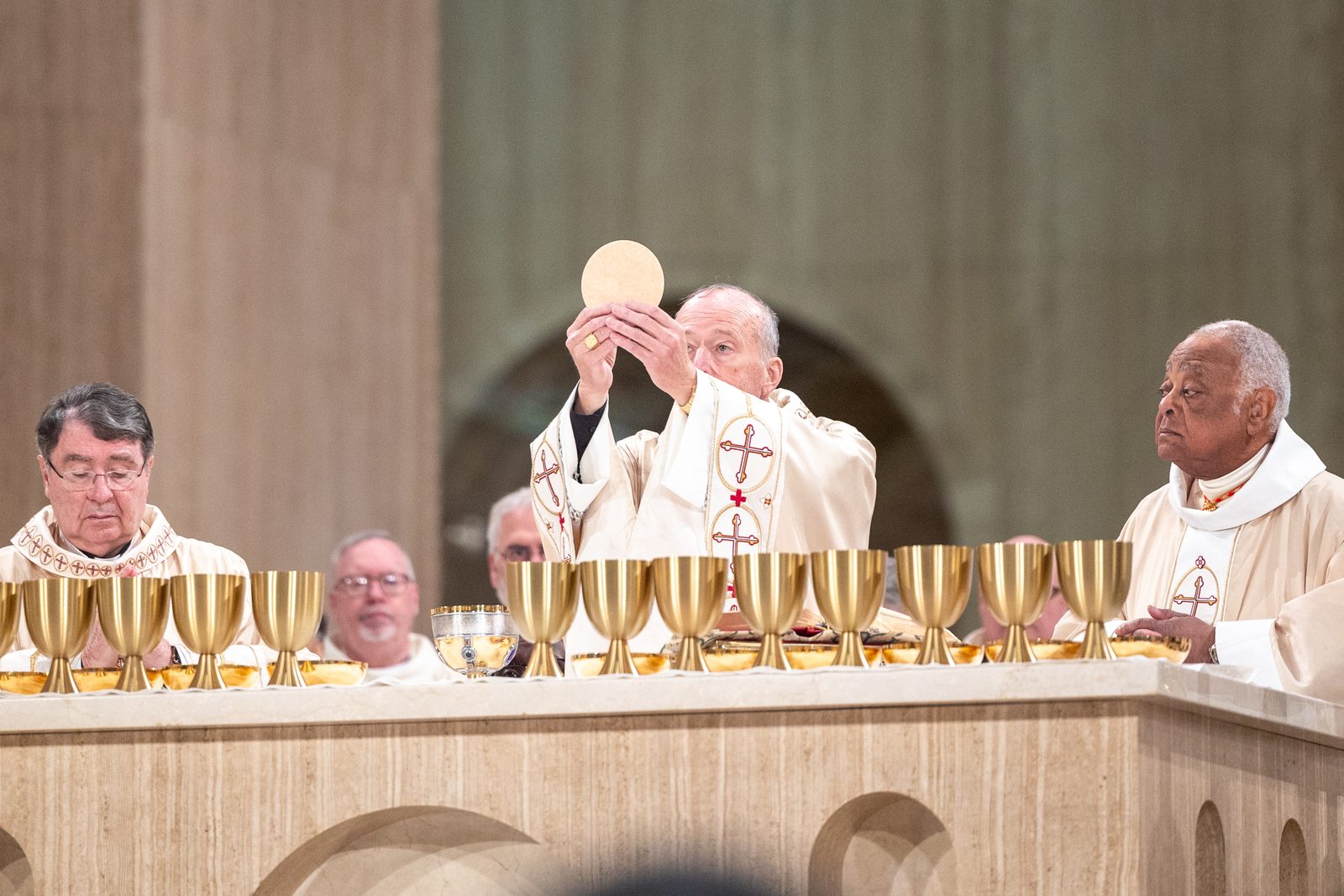Cardinal Robert McElroy, the new archbishop of Washington, elevates the Eucharist during the consecration of his Solemn Mass of Installation, which was held on March 11, 2025 at the Basilica of the National Shrine of the Immaculate Conception. The concelebrants at the Mass included, at left, Cardinal Christophe Pierre, the apostolic nuncio to the United States, and at right, Cardinal Wilton Gregory, the archbishop emeritus of Washington. (Catholic Standard photo by Mihoko Owada)