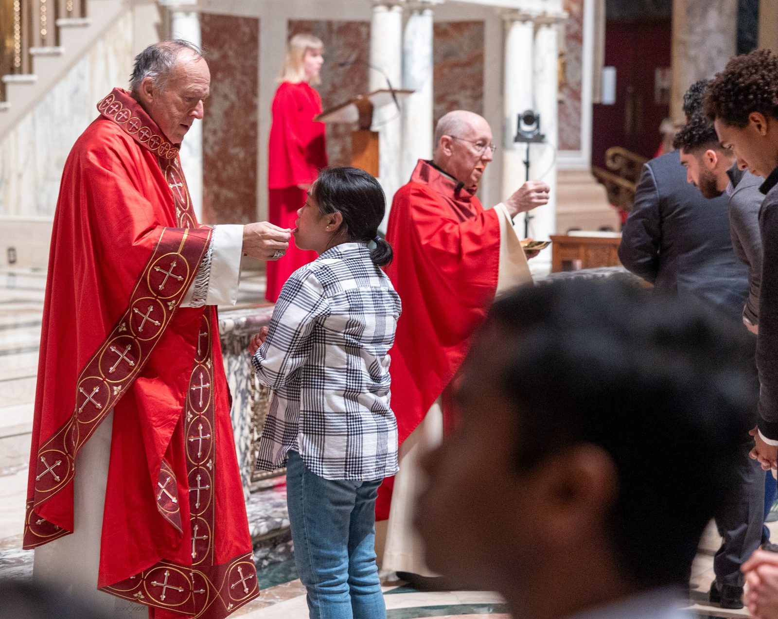 Washington Cardinal Robert W. McElroy, at left, gives Communion to a woman during the Palm Sunday Mass on April 13, 2025, at the Cathedral of St. Matthew the Apostle. At right, also distributing Communion was Msgr. W. Ronald Jameson, the rector of St. Matthew’s Cathedral. The liturgy commemorates Jesus’ triumphant entry into Jerusalem and begins the observance of Holy Week. (Catholic Standard photo by Mihoko Owada)