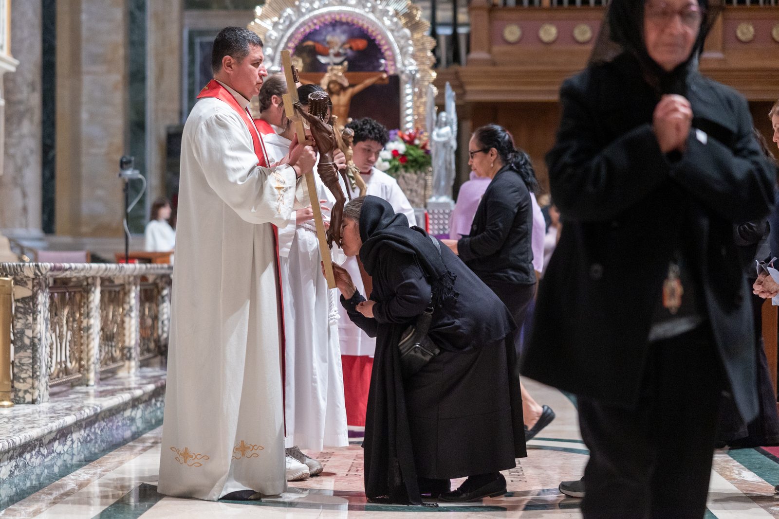 During a Good Friday liturgy for Spanish-speaking Catholics on April 18 at the Cathedral of St. Matthew the Apostle, Washington Auxiliary Bishop Evelio Menjivar holds a crucifix as a woman venerates it. The liturgy included a reading of the Passion and veneration of the cross, so people would remember Jesus’s sacrifice. (Catholic Standard photo by Mihoko Owada)