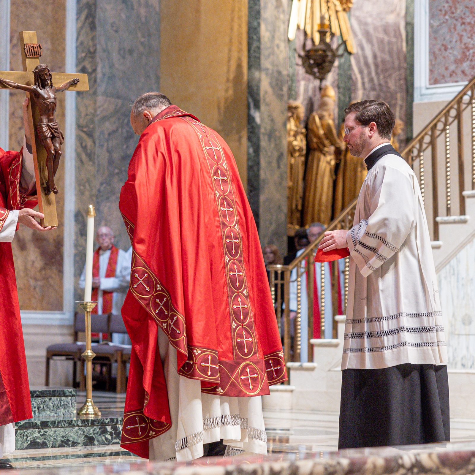 Cardinal Robert W. McElroy, the archbishop of Washington, bows as he venerates the cross during a Liturgy of the Lord’s Passion held on Good Friday, April 18, 2025, at the Cathedral of St. Matthew the Apostle. Deacon Robert Vince holds the cross at left. At right is Father Kevin Regan, the cardinal’s priest secretary. (Catholic Standard photo by Mihoko Owada)