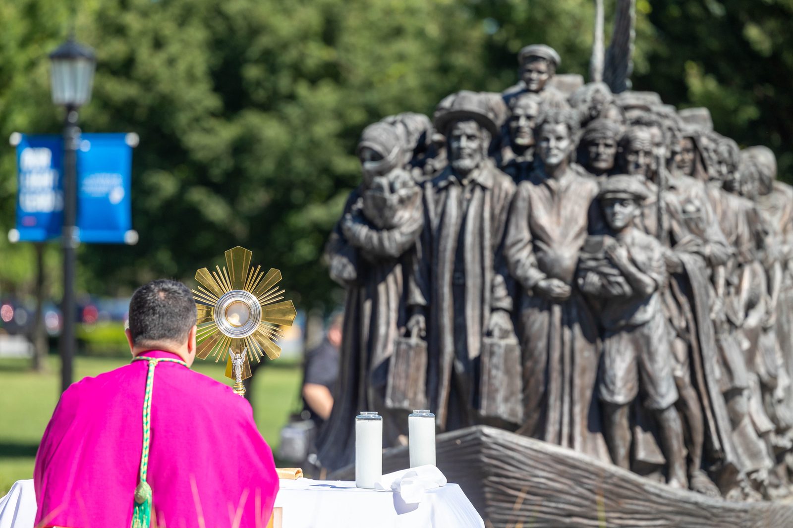 The procession stops to pray at the "Angels Unawares" sculpture at The Catholic University of America on June 8, 2024. ( CS photo by Mihoko Owada)