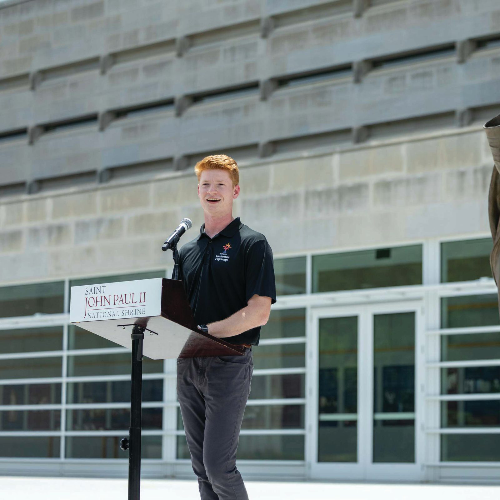 John Paul Flynn, one of the nine young adult “perpetual pilgrims” traveling with the Eucharist along the East Coast during the 2026 National Eucharistic Pilgrimage, speaks June 6 at the Saint John Paul II National Shrine in Northeast Washington, D.C. A native of Washington and a parishioner at Sacred Heart Church in Bowie, Flynn said “the call is for all of us to become a saint, to go to heaven, and to be with Jesus forever. And the best way to do that is through the sacraments.” (Catholic Standard photo by Mihoko Owada)