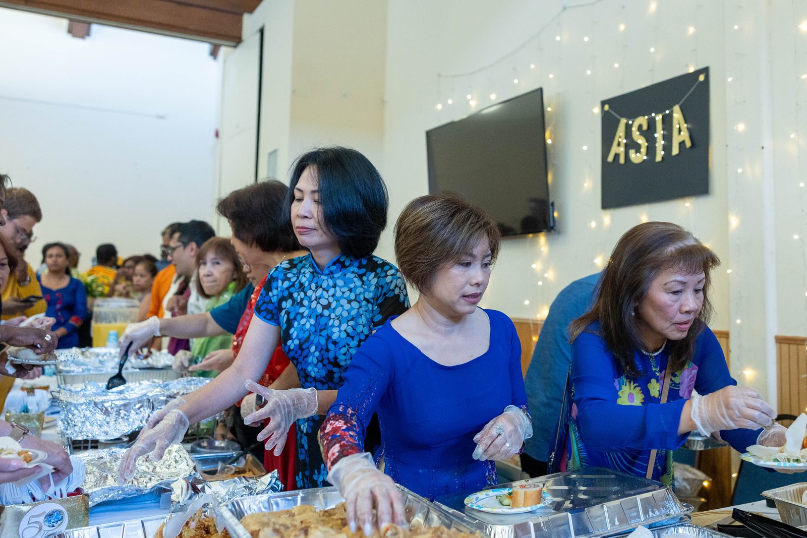 Women serve traditional Asian food at a June 30 reception marking the 50th anniversary of Mother Seton Parish in Germantown, Maryland. (Catholic Standard photos by Mihoko Owada)