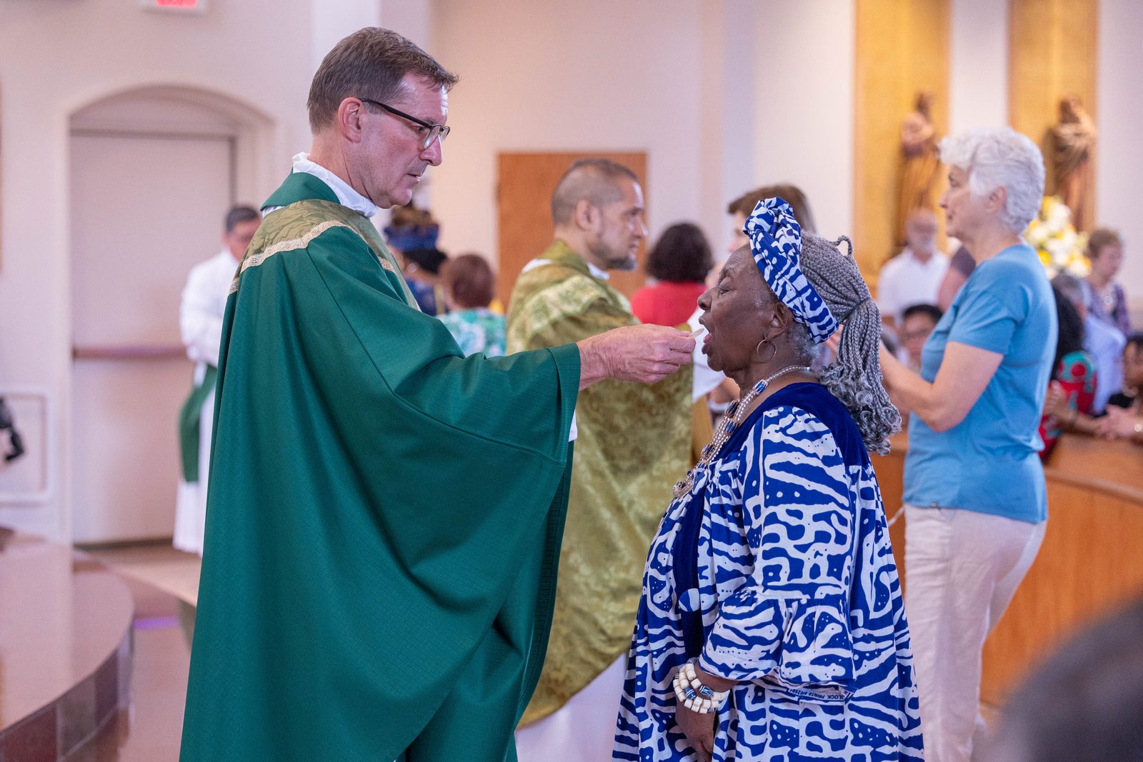 Father Lee Fangmeyer, the pastor of Mother Seton Parish in Germantown, gives Communion to a woman wearing traditional African dress during a June 30 Mass marking the Maryland parish’s 50th anniversary. (Catholic Standard photo by Mihoko Owada)