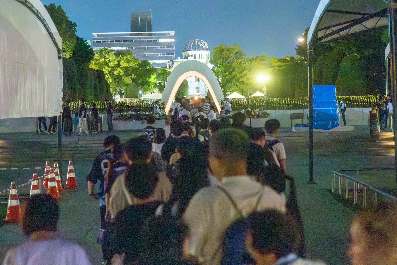 On the evening of Aug. 6, 2025, people line up in front of the Cenotaph for the A-bomb Victims at Hiroshima Peace Park to offer prayers. (Catholic Standard photo by Mihoko Owada)