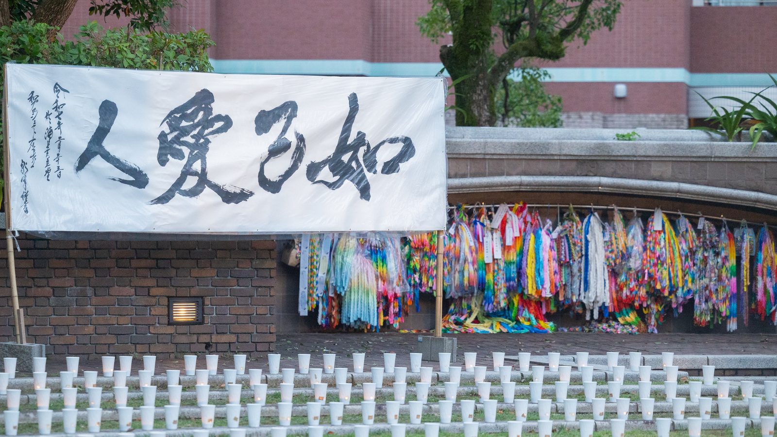 A banner with the words “Love Your Neighbor as Yourself” (left) and thousands of handmade origami cranes (symbols of peace) are displayed at the Nagasaki Atomic Bomb Hypocenter Park on August 8, 2025. (Catholic Standard photo by Mihoko Owada)