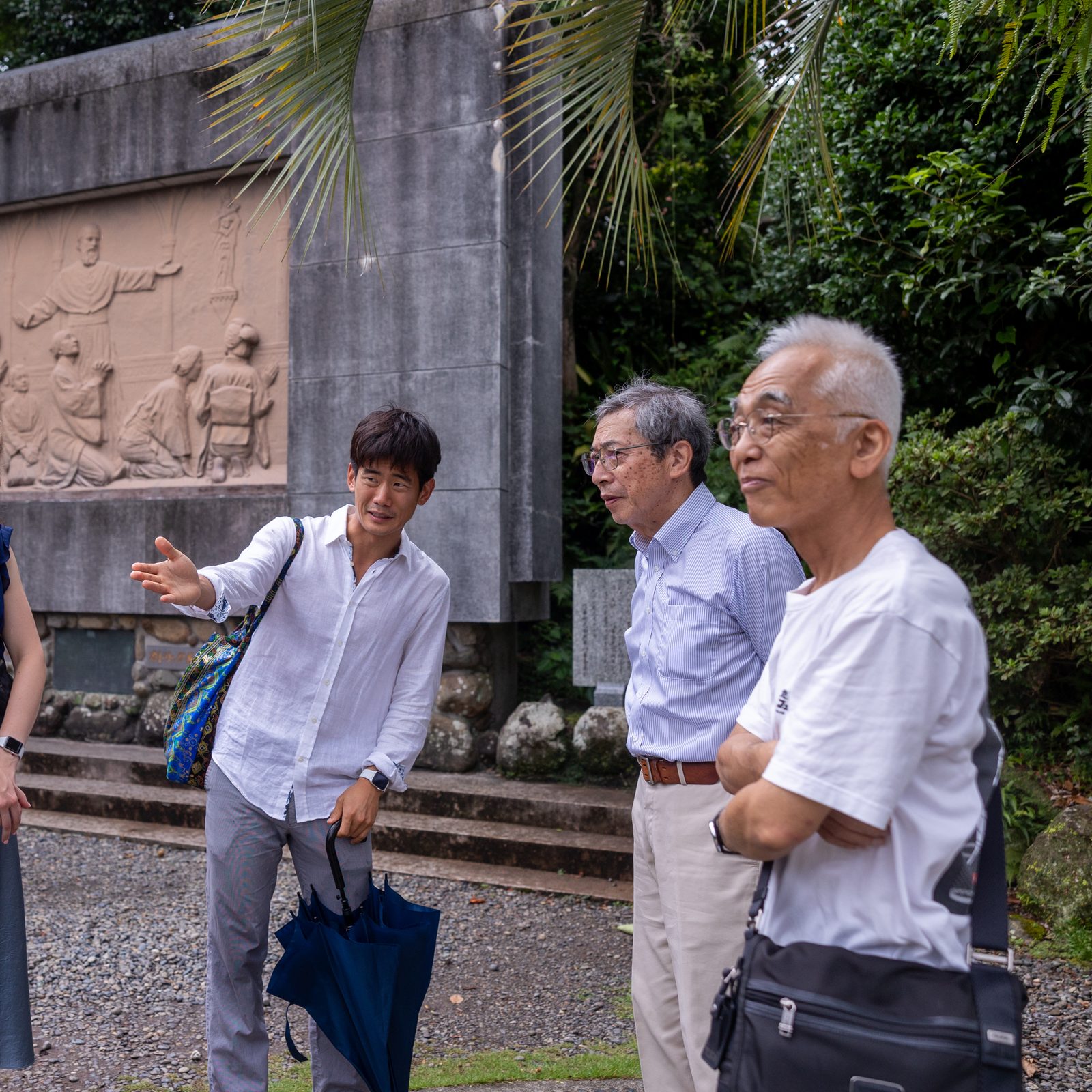 U.S. college students talk with Kojiro Moriuchi (second from right) after participating in Mass at Oura Cathedral in Nagasaki on the morning of Aug. 10, 2025. Moriuchi's great-grandmother played a pivotal role in the discovery of hidden Japanese Christians who had kept the faith despite years of persecution there, an event that occurred at Oura Cathedral in 1865. Her figure is carved on the far left of the relief behind them. (Catholic Standard photo by Mihoko Owada)