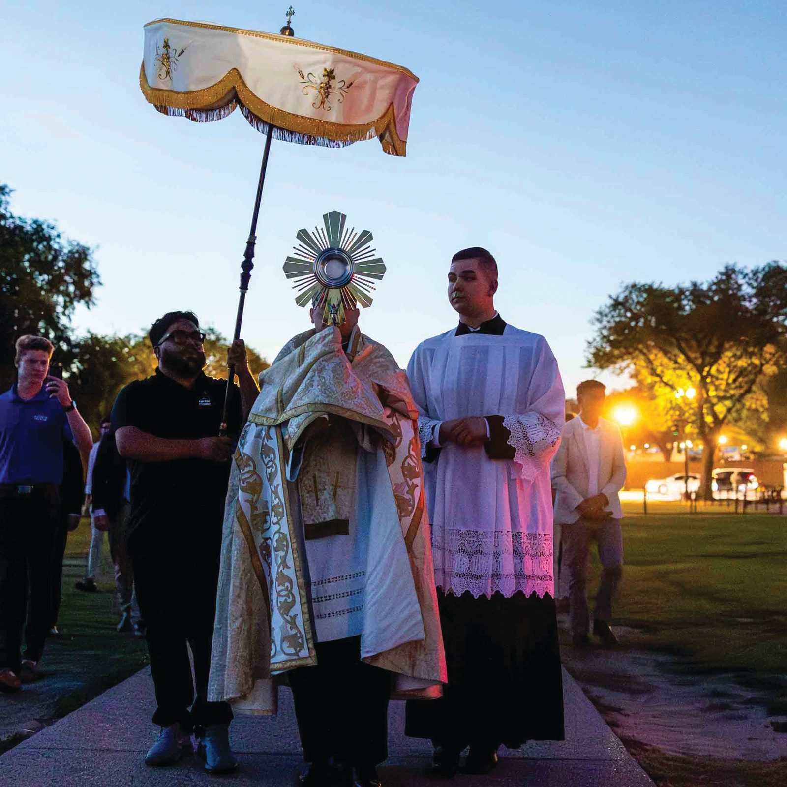 Father Charles Trullols, director of the Catholic Information Center, carries the Blessed Sacrament near the Washington Monument during the National Eucharistic Pilgrimage’s arrival in Washington on June 5, 2026. Pilgrims gathered on the National Mall for a Eucharistic blessing for the nation. John Paul Flynn, one of nine Catholic young adult perpetual pilgrims joining the pilgrimage, walks at left. (Catholic Standard photo by Mihoko Owada)