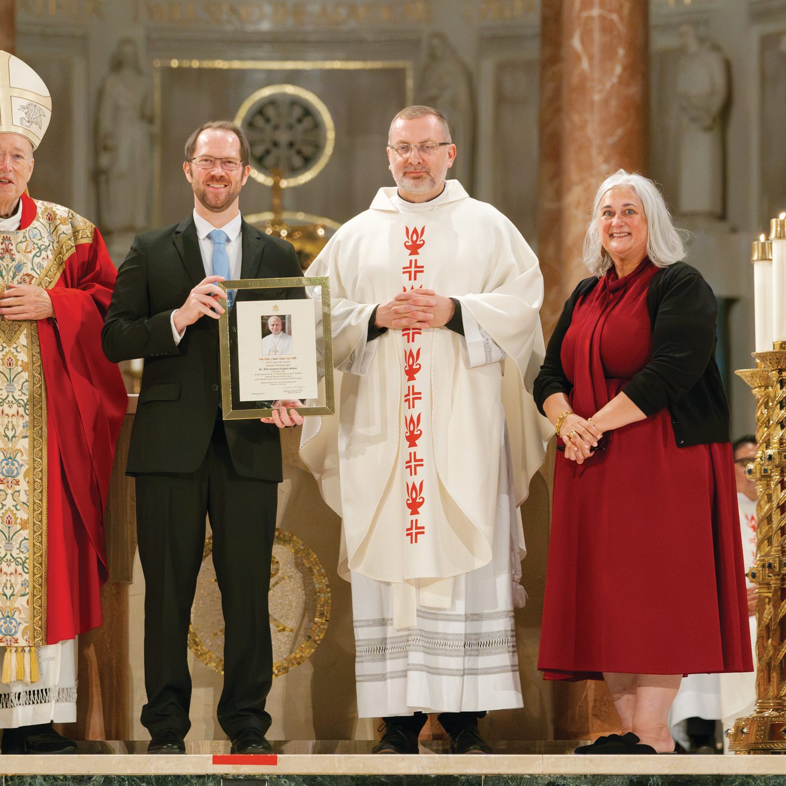 St. Jude Regional Catholic School in Rockville, Maryland, was honored for its 70th anniversary during the Opening of Schools Mass for the Roman Catholic Archdiocese of Washington on Aug. 24 at the Basilica of the National Shrine of the Immaculate Conception. From left to right are Washington Cardinal Robert W. McElroy; Mark Crimans, St. Jude’s principal; Father Pawel Sass, the pastor of the Shrine of St. Jude; and Kelly Branaman, the Secretary for Catholic Schools and Superintendent of Schools for the Archdiocese of Washington. (Catholic Standard photo by Nicole Olea)