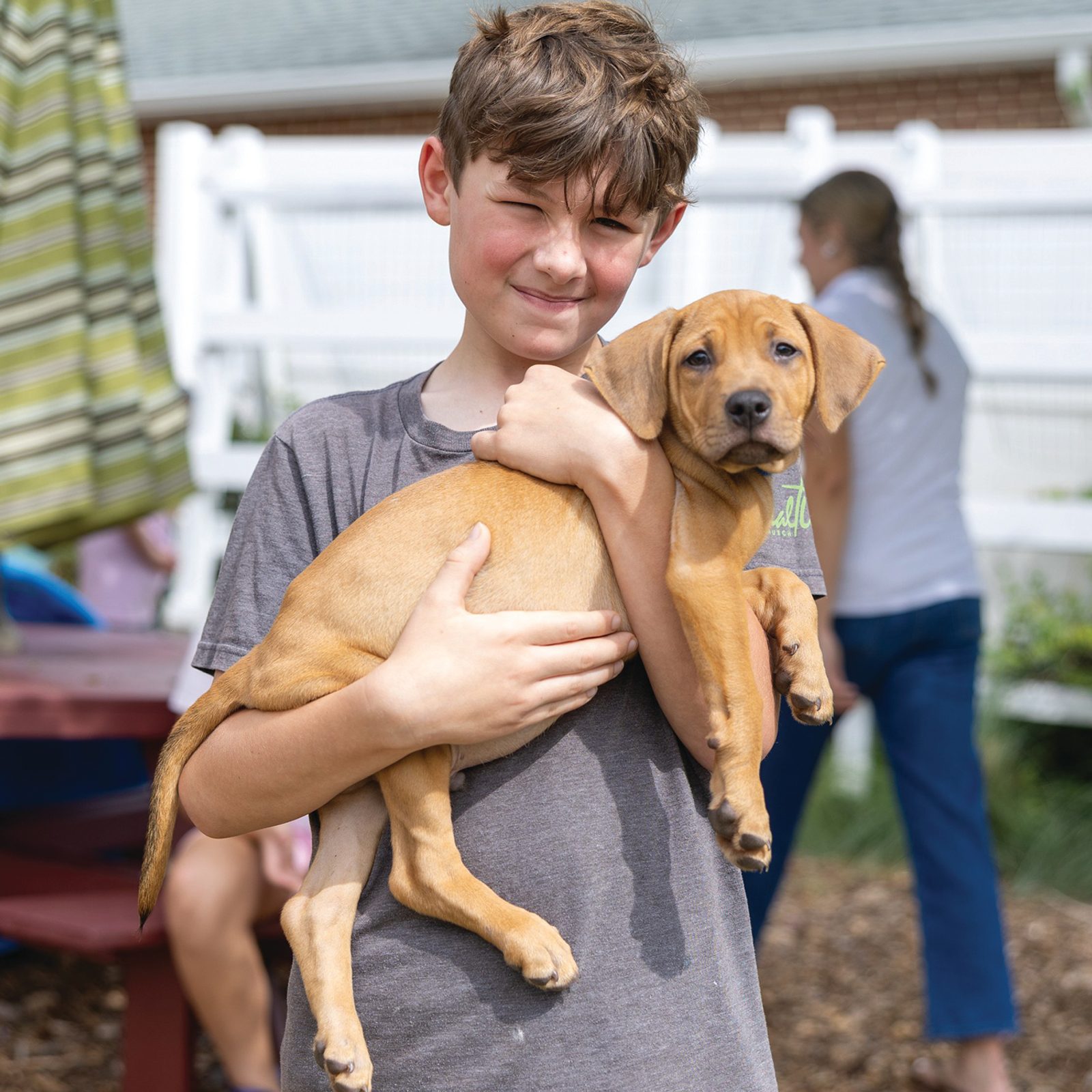 A camper holds a rescue puppy from Operation Paws for Homes during Puppy Camp on Ju-ly 21 at St. John’s Summer Program at St. John Francis Regis Parish in Hollywood, Maryland. During the camp, children spend time handling and caring for the puppies, offering toys, petting them and learning how to approach animals patiently. (Catholic Standard photo by Mihoko Owada)