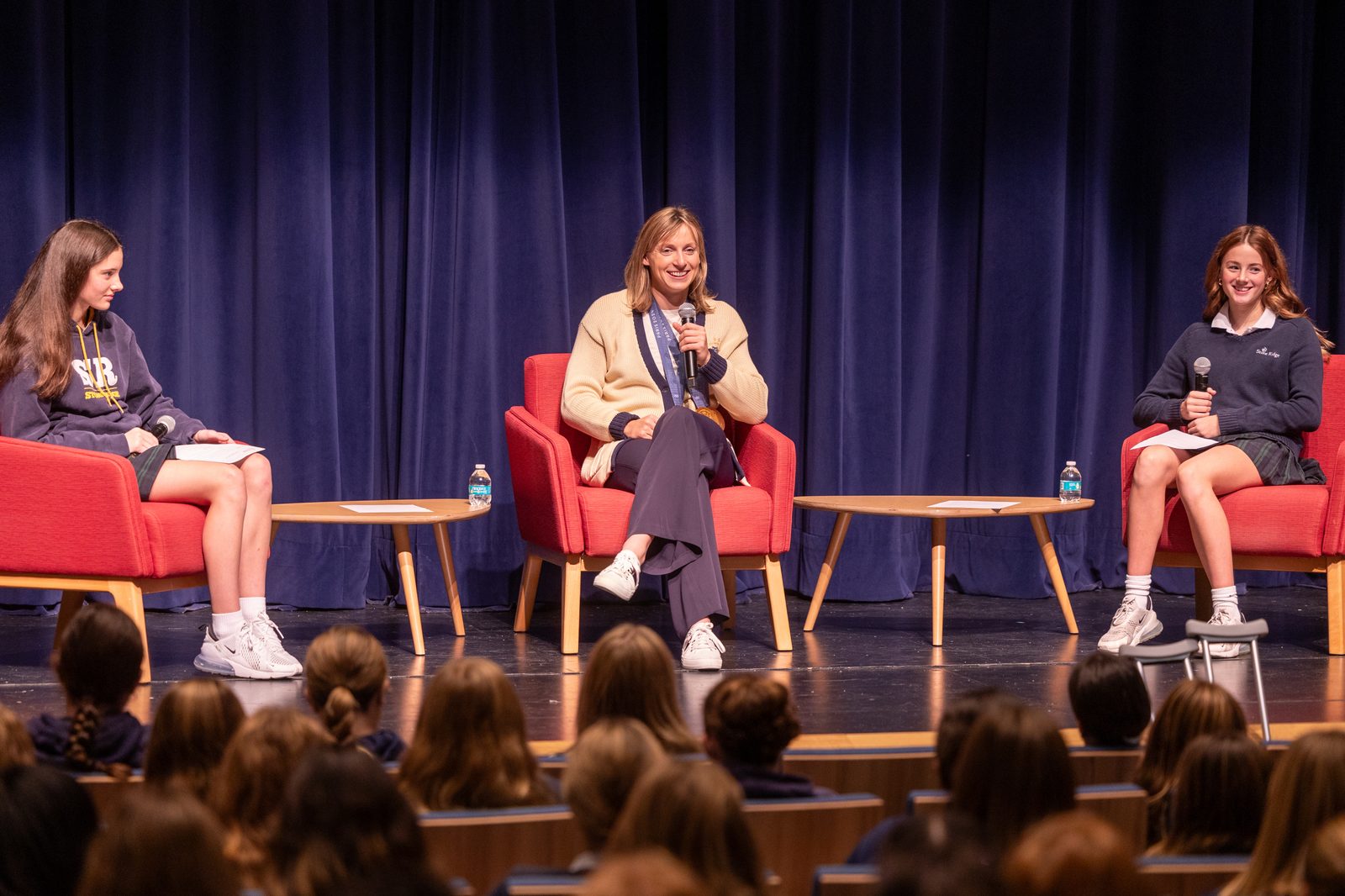 Olympic champion swimmer Katie Ledecky, at center, returns to her alma mater, Stone Ridge School of the Sacred Heart in Bethesda, Maryland, for a visit with students on Oct. 22, 2024. During a session with the Stone Ridge Middle School in the Cokie Boggs Roberts Theater at the school’s Mater Center, Ledecky answered questions from students, including eighth grader Ainsley Bell at left and seventh grader Caroline Davey at right. (Catholic Standard photo by Mihoko Owada)