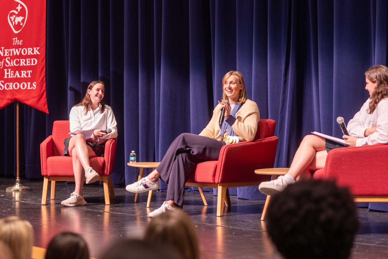 Olympic champion swimmer Katie Ledecky, at center, returns to her alma mater, Stone Ridge School of the Sacred Heart in Bethesda, Maryland, for a visit with students on Oct. 22, 2024. During a session with the Stone Ridge Upper School in the Cokie Boggs Roberts Theater at the school’s Mater Center, Ledecky answered questions from students, including seniors Isabelle Bernasek at left and Cameron House at right. (Catholic Standard photo by Mihoko Owada)