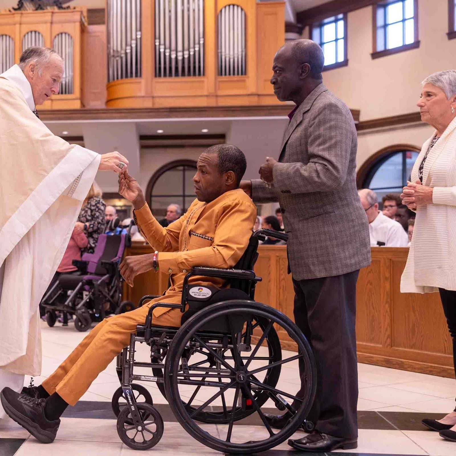 During the White Mass on Oct. 26 at Our Lady of Mercy Church in Potomac, Cardinal Robert W. McElroy gives Communion to Kobe Cudjoe, who is followed by his father James Cudjoe. (Catholic Standard photo by Mihoko Owada)