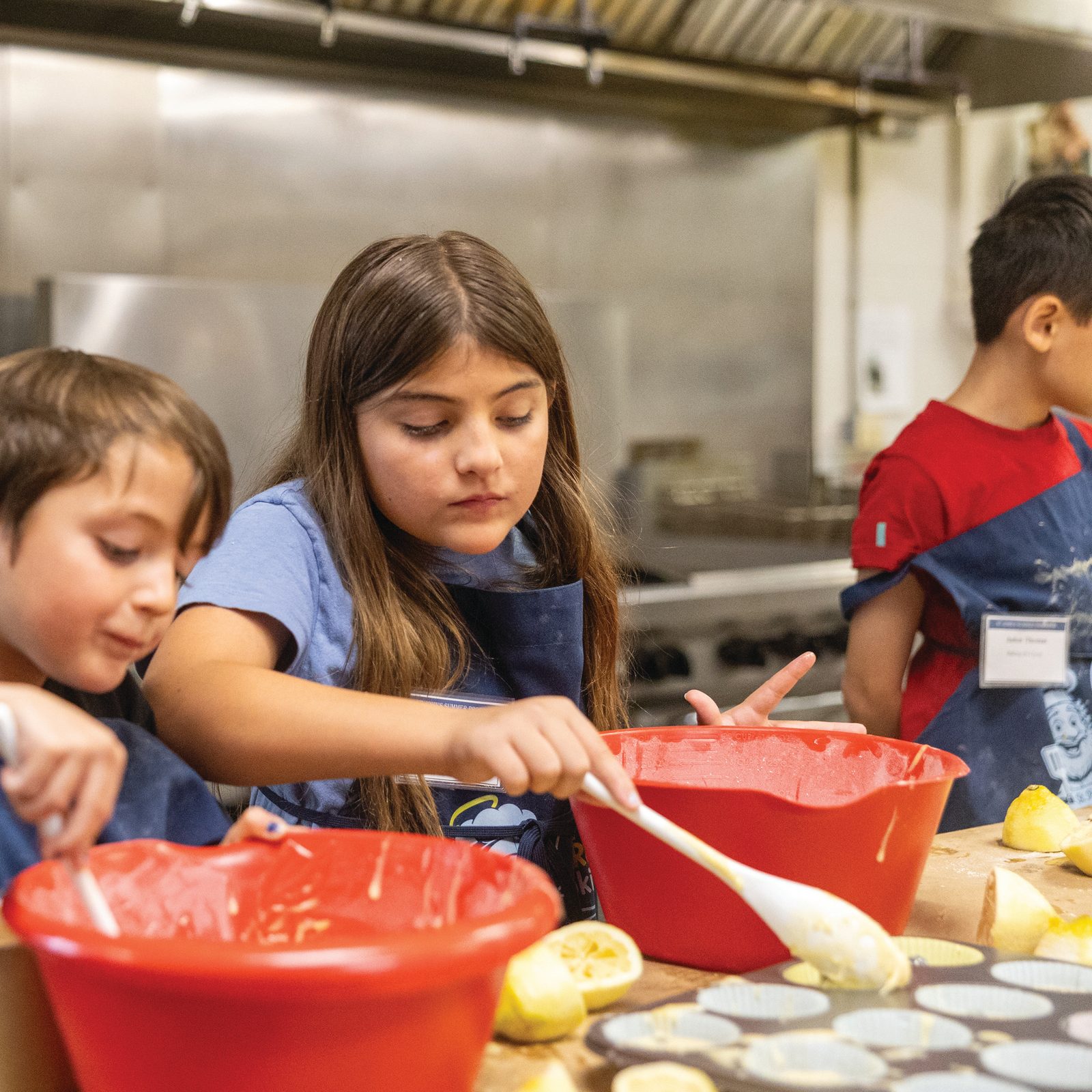 Campers stir batter while preparing muffins during a cooking camp at St. John’s Summer Program on July 21 at St. John Francis Regis Parish in Hollywood, Maryland. Children meas-ure ingredients, squeeze lemons, crack eggs and work together in the school’s industrial kitchen as part of the program’s hands-on activities. (Catholic Standard photo by Mihoko Owada)