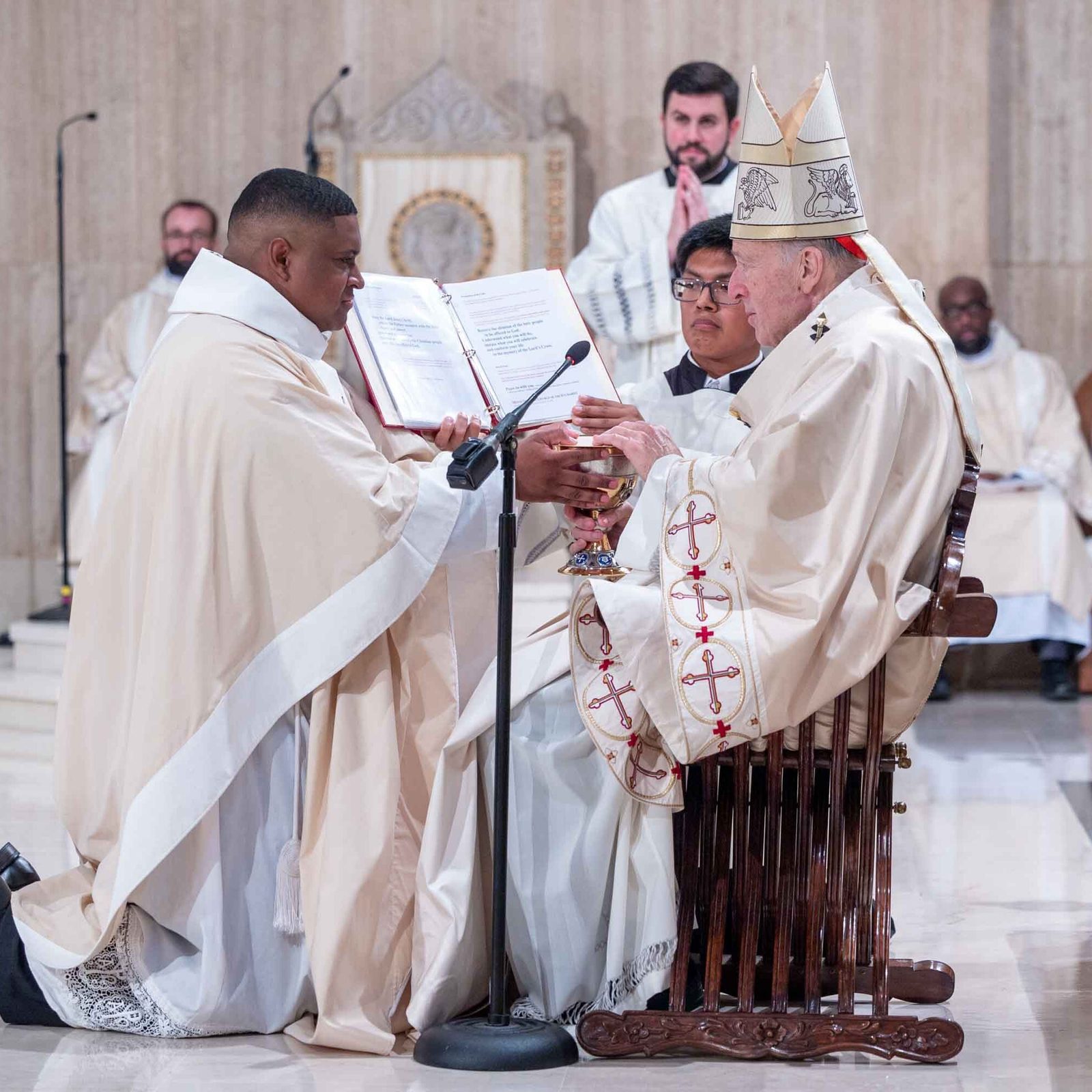 At the Mass for the Ordination of Priests on June 20, 2026 at the Basilica of the National Shrine of the Immaculate Conception, Cardinal Robert W. McElroy in the photo above presents the bread and wine brought up by the community to newly ordained Father Jessiah Rojas as a sign of his presiding at the Eucharist. In the photo below, Cardinal McElroy presents the bread and wine to newly ordained Father Brendan Parlett. (Catholic Standard photos by Mihoko Owada)