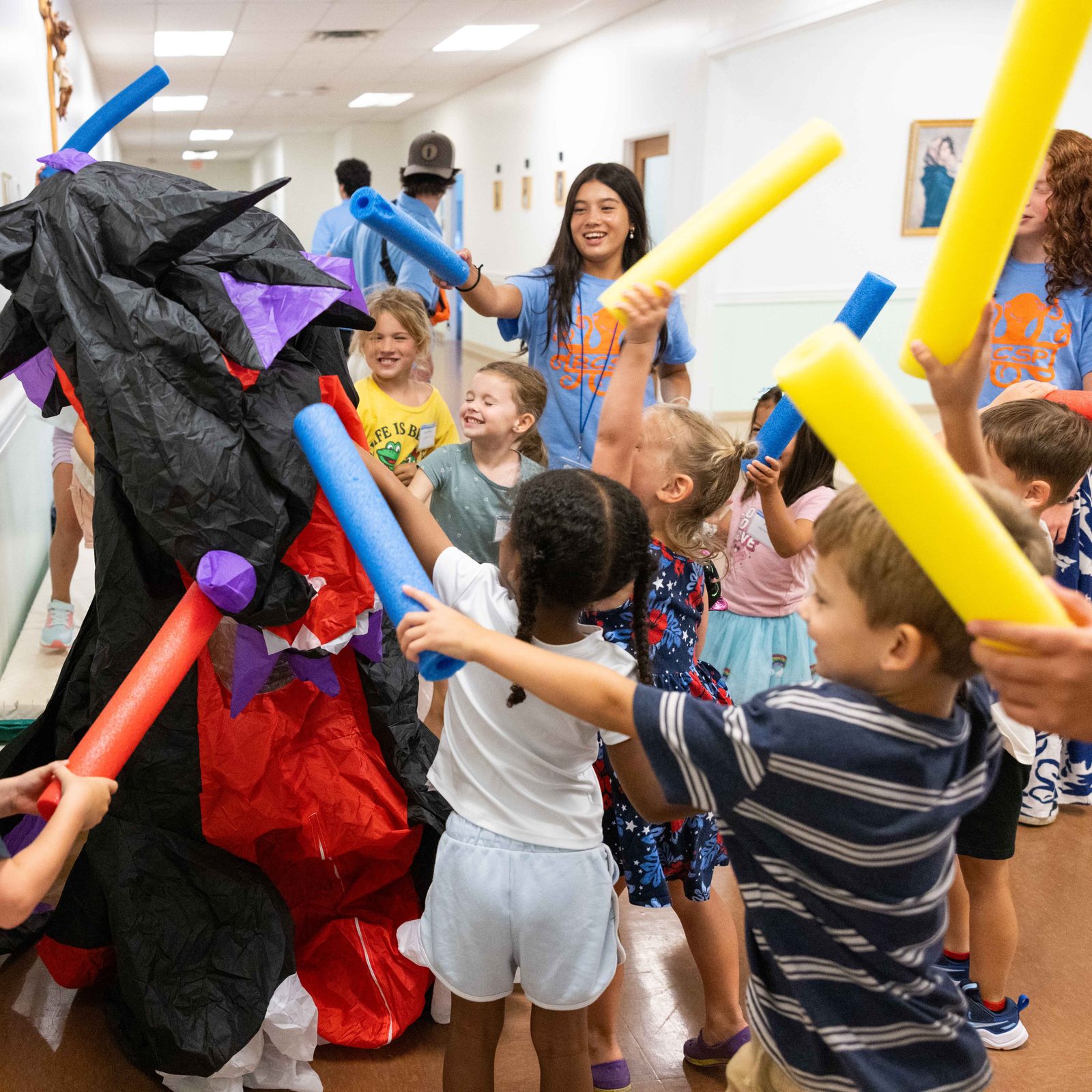 After hearing the story of St. George and the dragon, campers and teen volunteers at the Rockville Catholic Summer Program on Aug. 5 at St. Patrick’s Parish wield soft foam pool noodles and attack a volunteer wearing a dragon costume. (Catholic Standard photo by Andrew Biraj)