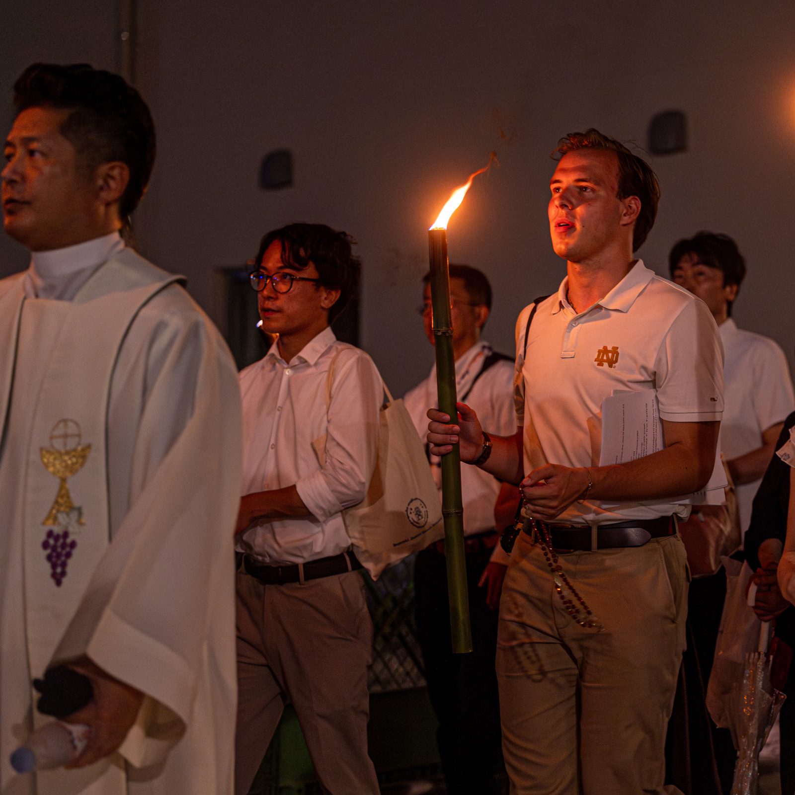 La gente participa en una procesión con antorchas al Parque de la Paz de Nagasaki. La catedral de Urakami, que se ve al fondo, fue reconstruida y dedicada en 1959 en el sitio de la catedral original destruida en el bombardeo del 9 de agosto de 1945. En la procesión participaron estudiantes universitarios estadounidenses integrantes de una Peregrinación de Paz para conmemorar los aniversarios de los bombardeos atómicos de Hiroshima y Nagasaki.