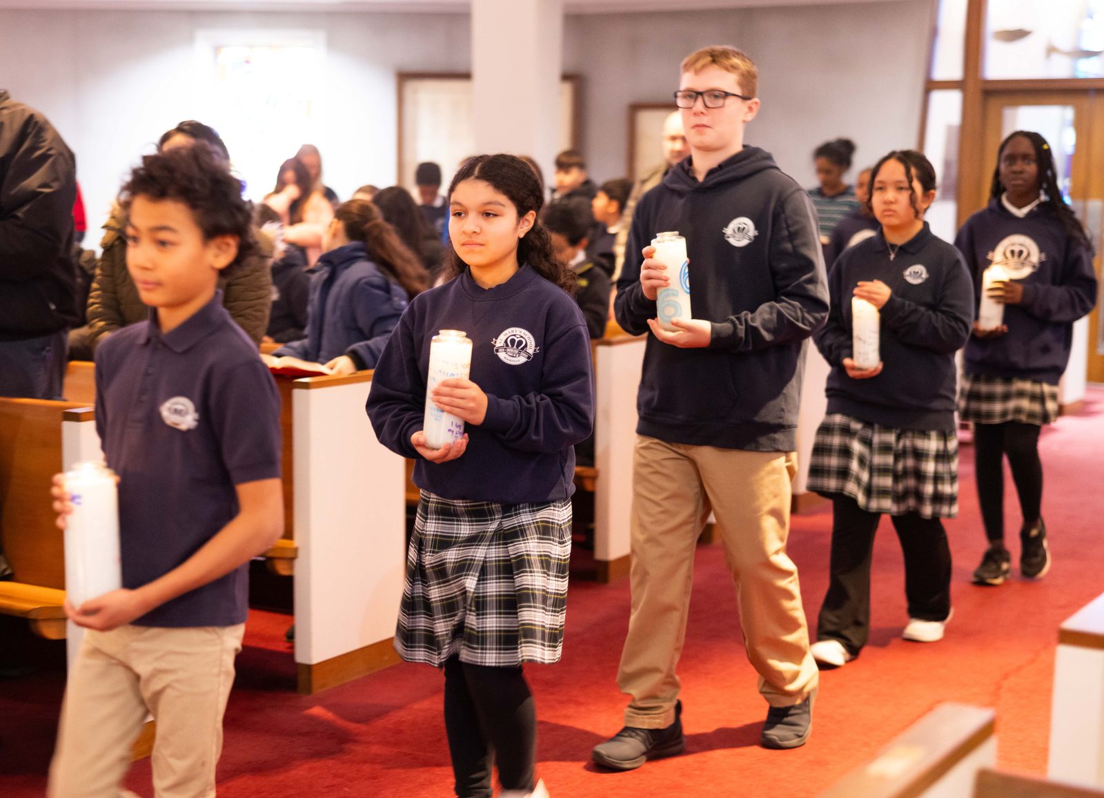 Students from St. Mary’s School in Rockville, Maryland, participating in a Candlemas procession carry candles to the altar at the beginning of a Jan. 31, 2025 Mass at St. Mary’s Church included, from left to right, Asher Cook, a fourth grader; Sofia Munoz, a fifth grader; Michael Atlee, a sixth grader; Thao Nguyen, a seventh grader; and Fréd'Oline Marogha Mbadinga-Zinsou, an eighth grader. Candlemas Day takes place on Feb. 2 and commemorates the presentation of Jesus at the Temple and the purification of the Blessed Virgin Mary. (Catholic Standard photo by Andrew Biraj)