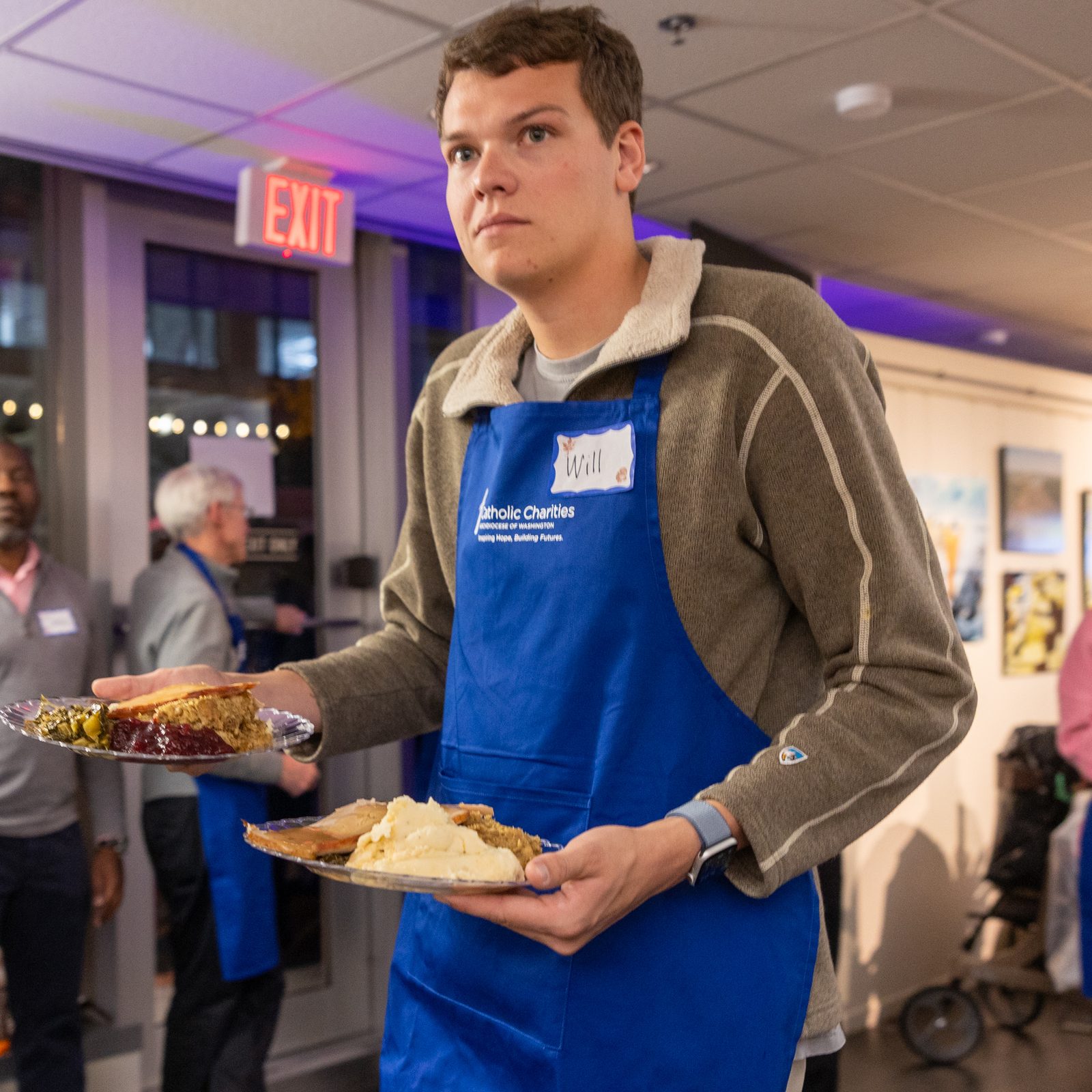 A volunteer with Catholic Charities brings plates of food to guests at the Nov. 26 Thanksgiving dinner given through Catholic Charities’ St. Maria’s Meals program and hosted by Pepco at its Edison Place Gallery in downtown Washington, D.C. (Catholic Standard photos by Mihoko Owada)