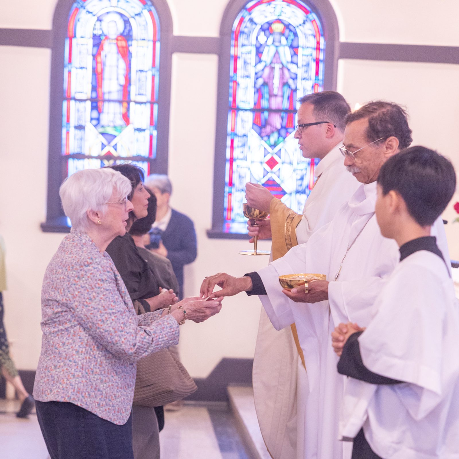 Washington Auxiliary Bishop Roy E. Campbell Jr. (at right center) and Father Stefan Megyery (third from right), the pastor of Epiphany Parish in Washington, D.C., give Communion to people at a May 18, 2025 Mass at Epiphany Catholic Church marking the parish’s 100th anniversary. (Catholic Standard photo by Mihoko Owada)