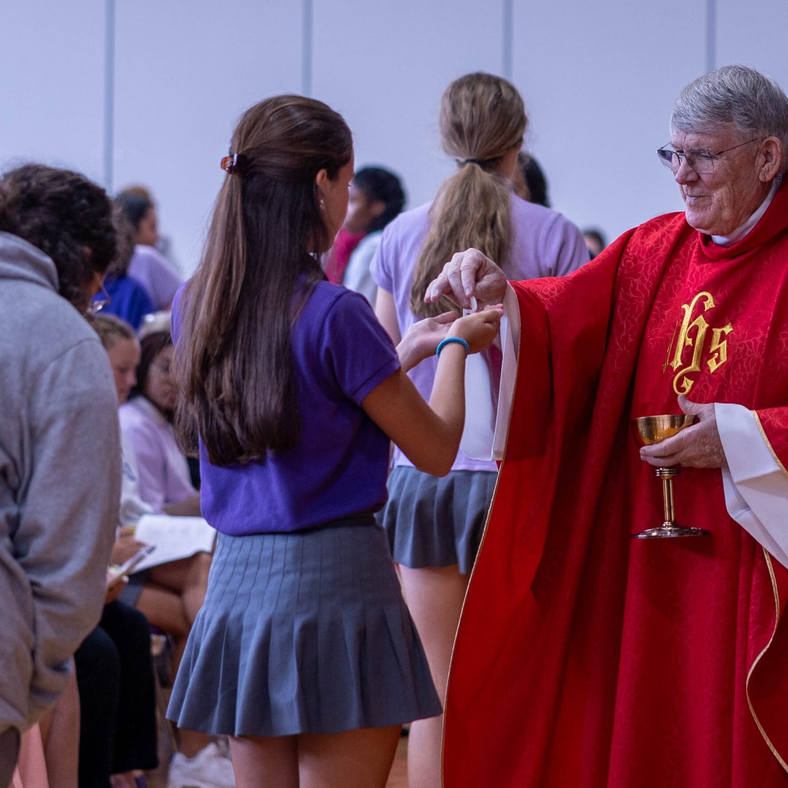 Msgr. John Enzler gives Communion to a student during a school-wide Mass celebrated by Washington Cardinal Wilton Gregory on Sept. 13, 2024 to mark the Feast of the Exaltation of the Holy Cross. (Catholic Standard photo by Mihoko Owada)