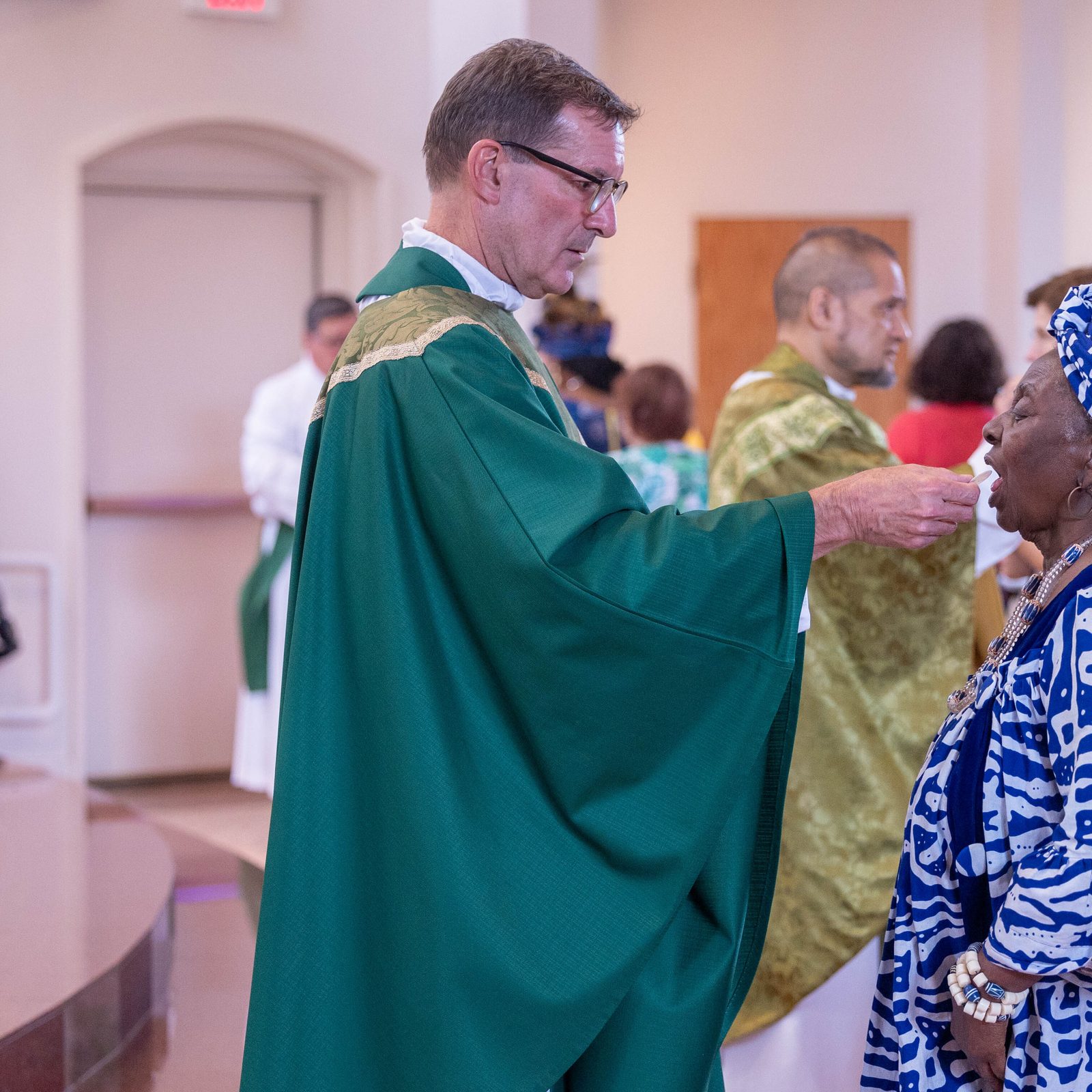 Father Lee Fangmeyer, the pastor of Mother Seton Parish in Germantown, gives Communion to a woman wearing traditional African dress during a June 30 Mass marking the Maryland parish’s 50th anniversary. (Catholic Standard photo by Mihoko Owada)