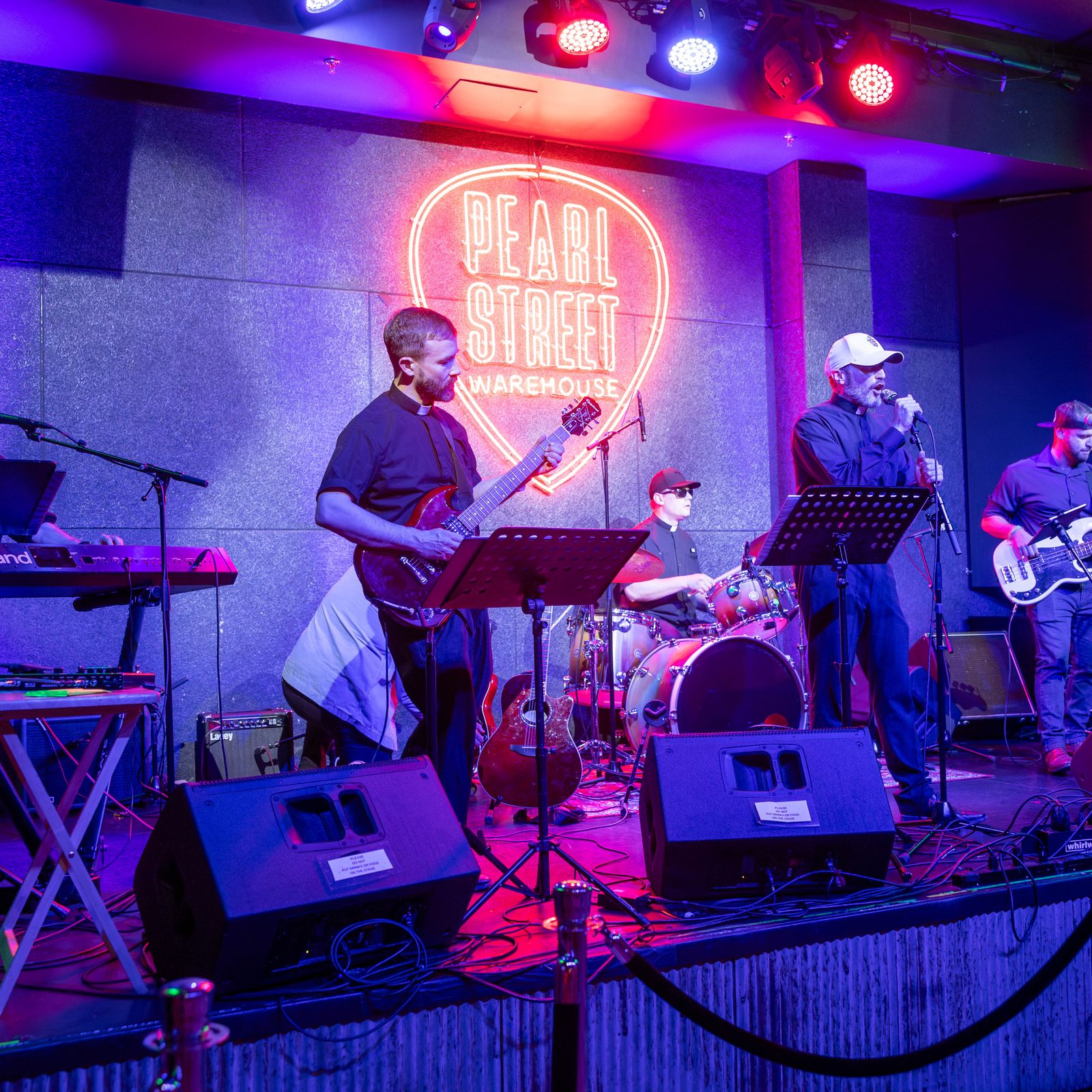 Iter, a band of local priests, plays during a May 20 concert at the Pearl Street Warehouse in Washington, D.C. From left to right are Father John Benson on keyboards; Father Phil Ilg playing the guitar; Father Jan Pietryga, the band’s drummer; Father Daniele Rebeggiani singing; guitarist Gabriel Barbieri; and Father Saulo Vicente, who sang and played the tambourine. (Catholic Standard photo by Mihoko Owada)