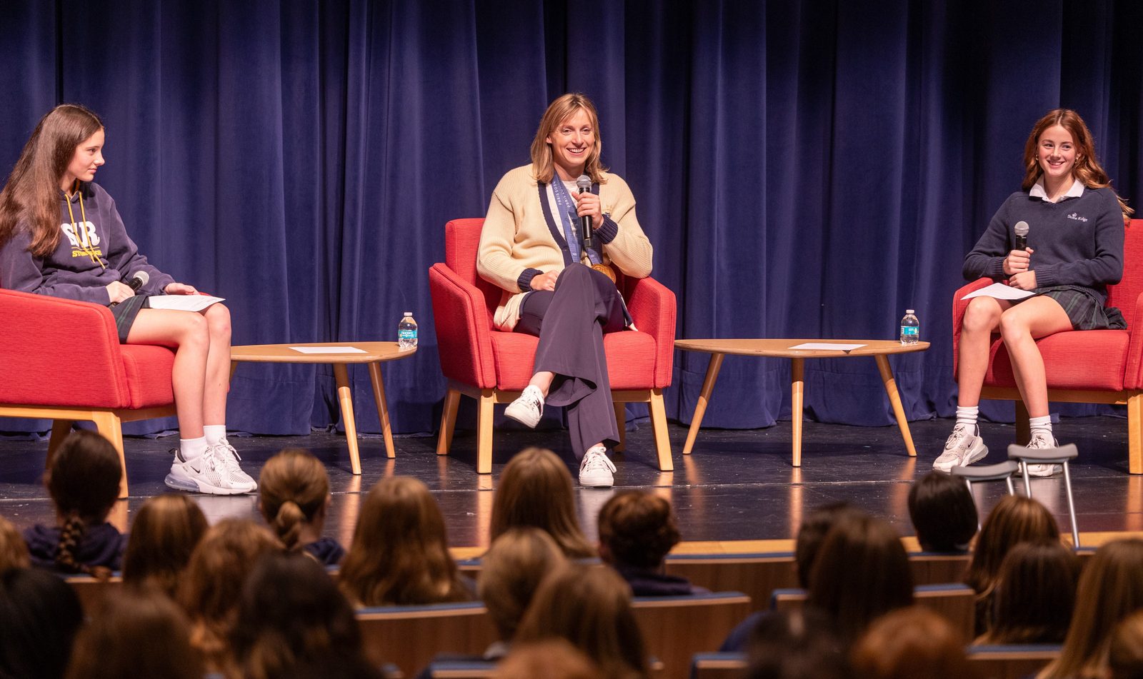 Olympic champion swimmer Katie Ledecky, at center, returns to her alma mater, Stone Ridge School of the Sacred Heart in Bethesda, Maryland, for a visit with students on Oct. 22, 2024. During a session with the Stone Ridge Middle School in the Cokie Boggs Roberts Theater at the school’s Mater Center, Ledecky answered questions from students, including eighth grader Ainsley Bell at left and seventh grader Caroline Davey at right. (Catholic Standard photo by Mihoko Owada)