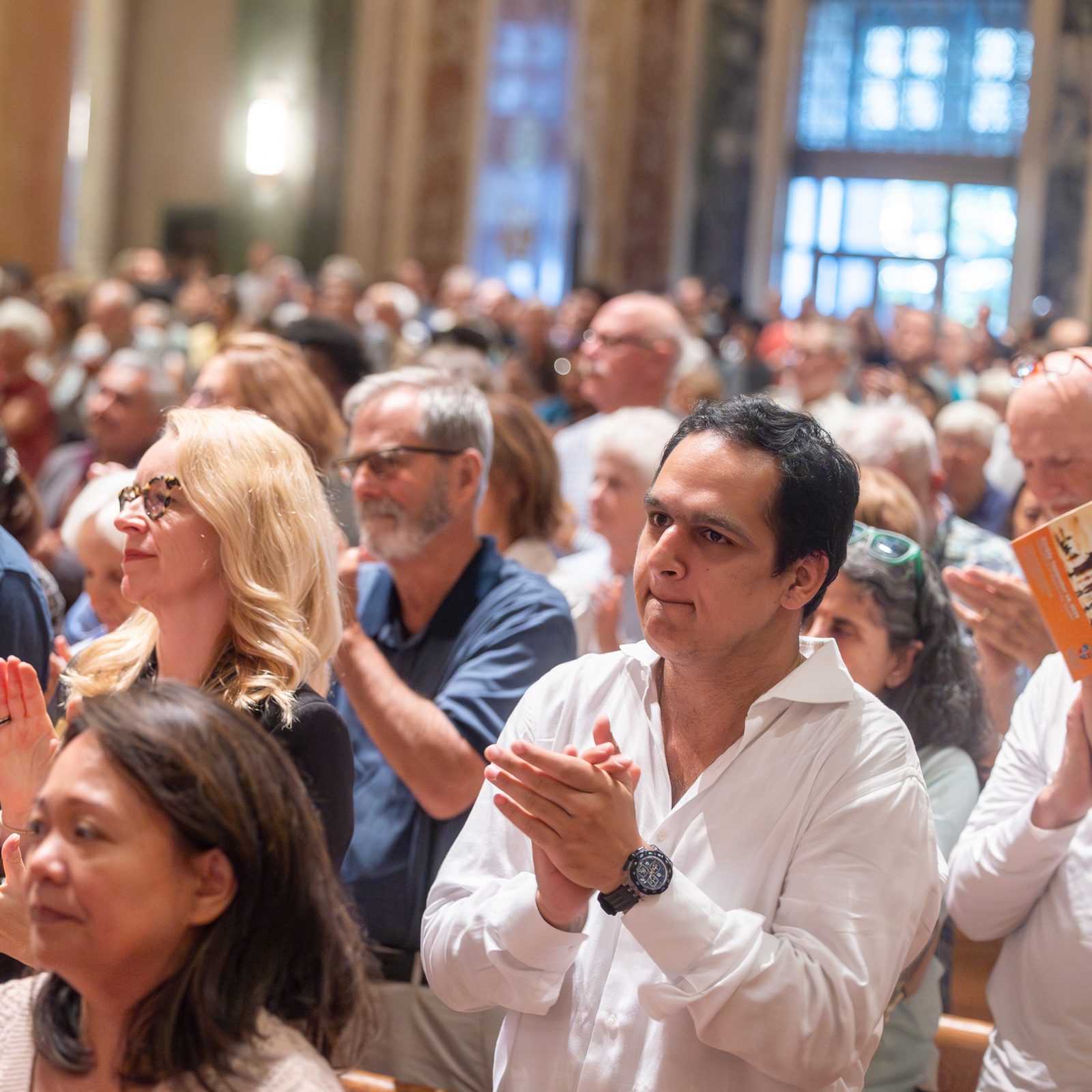 Feligreses aplauden de pie al cardenal Robert McElroy, luego de concluir su homilía, durante la misa por la Jornada Mundial del Migrante y del refugiado celebrada, en la catedral de San Mateo Apóstol, el 28 de septiembre de 2025.