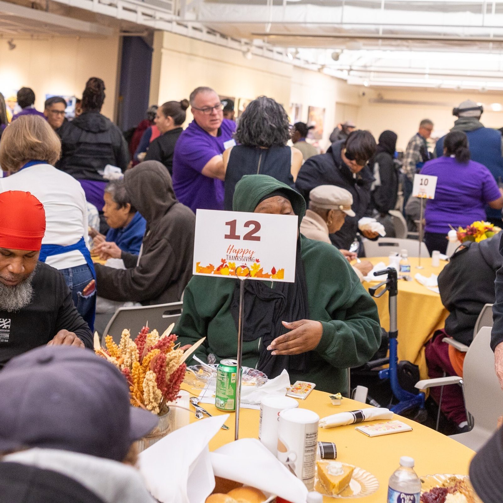 Msgr. John Enzler (at right), the mission advocate for Catholic Charities of The Roman Catholic Archdiocese of Washington, greets guests at the Nov. 26 Thanksgiving dinner given through Catholic Charities’ St. Maria’s Meals program and hosted by Pepco at its Edison Place Gallery in downtown Washington, D.C. (Catholic Standard photos by Mihoko Owada)