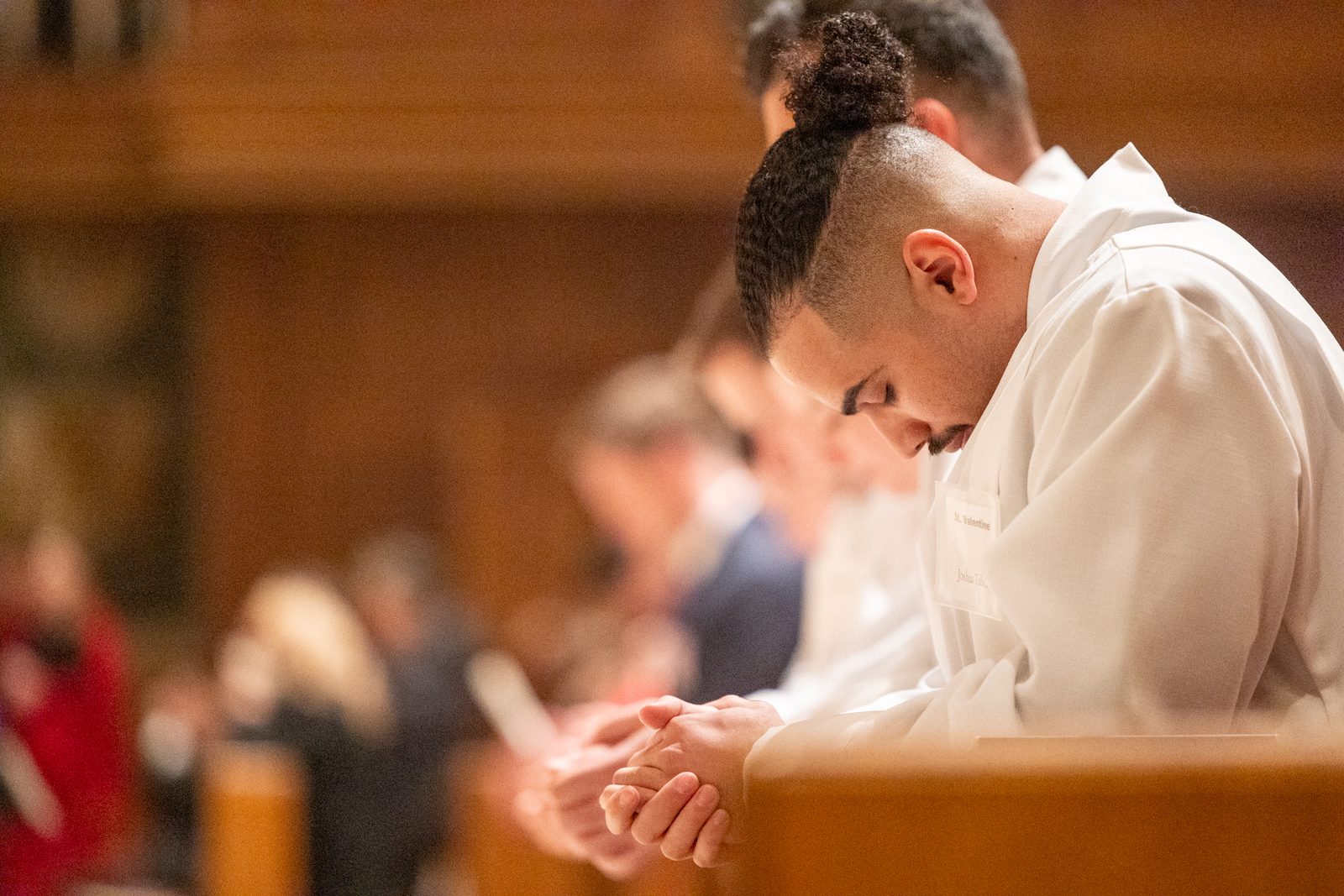 A newly baptized man, Joshua Taborn, wears his white baptismal garment as he prays during the Easter Vigil on March 30 at St. Matthew’s Cathedral in Washington, D.C. (Catholic Standard photo by Mihoko Owada)