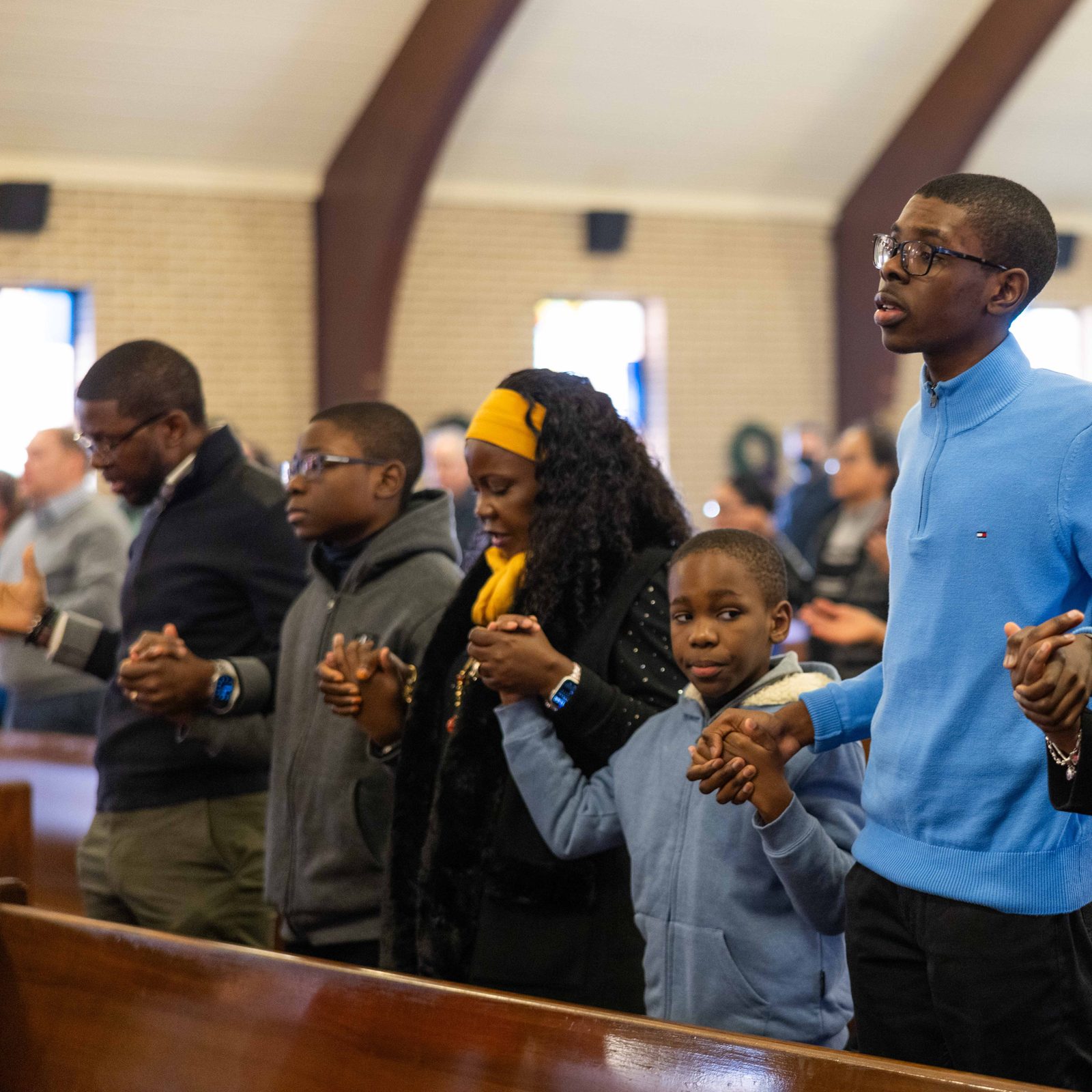 Family members join hands to pray the Our Father during a Dec. 14 Mass at St. Hugh of Grenoble Church in Greenbelt, Maryland. (Catholic Standard photo by Andrew Biraj)