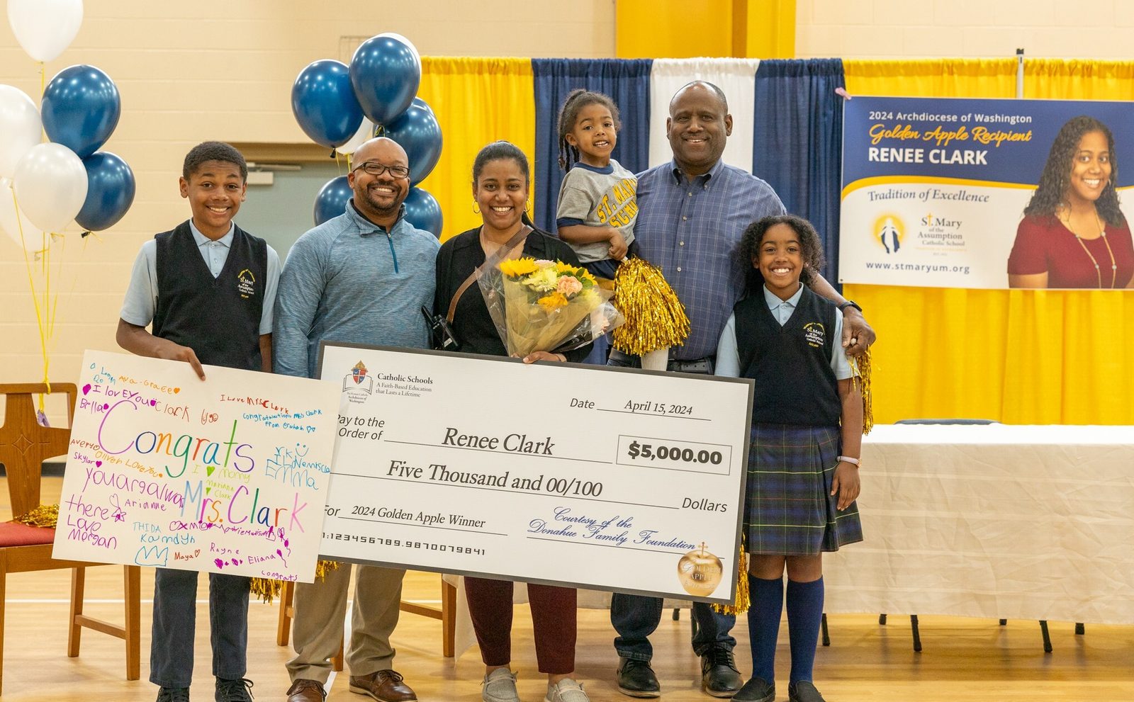 At the surprise assembly where Renee Clark, the resource teacher at St. Mary of the Assumption Catholic School in Upper Marlboro, learned that she is a 2024 Golden Apple Award-winning teacher, she was joined by her husband Marcus Clark and by their three children attending the school, and also by her father, Tracy Dorsey. From left to right are Darren Clark, an eighth grader there; Marcus Clark; Renee Clark; Mariana Clark, a kindergarten student there; Tracy Dorsey; and Karina Clark, a sixth grader there. (Catholic Standard photo by Mihoko Owada)