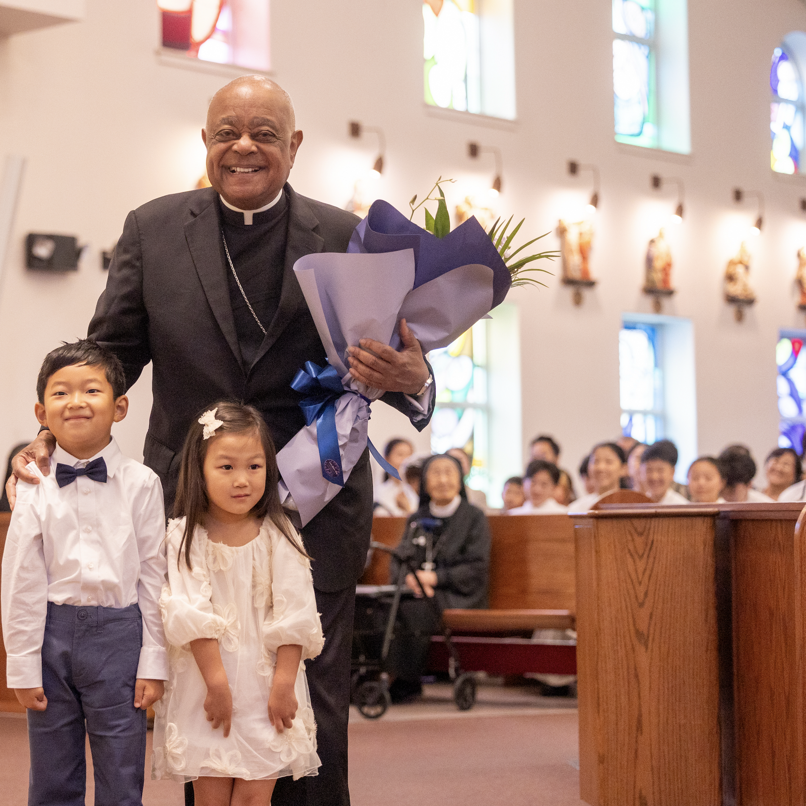 A young boy and a girl presented flowers to Washington Cardinal Wilton Gregory before he celebrated a Mass on Sept. 29, 2024 marking the 50th anniversary of St. Andrew Kim Parish in Olney, Maryland, that serves Korean Catholics. (Catholic Standard photos by Mihoko Owada)