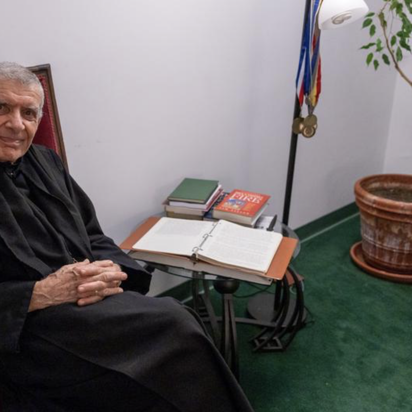 Abbot James Wiseman relaxes in his office at St. Anselm's Abbey in Washington on Dec. 11, 2024, sitting next to a file of retyped handwritten letters sent to him by his mother. (Catholic Standard photo by Mihoko Owada)