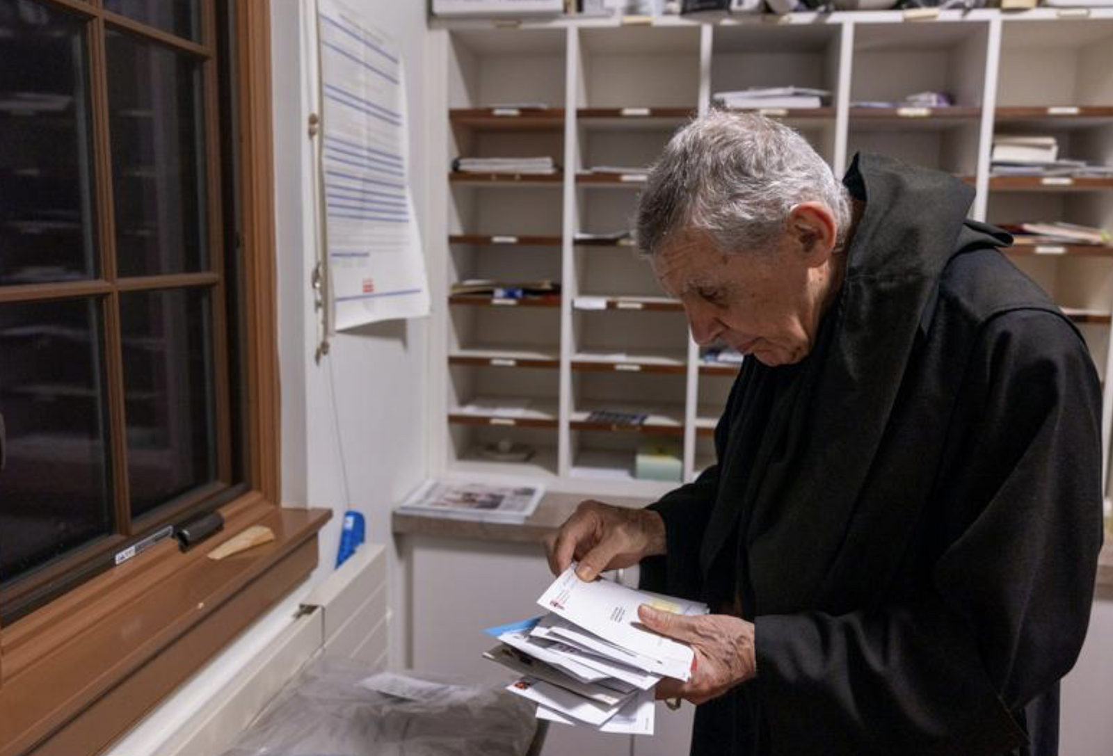 Abbot James Wiseman organizes the mail that the Benedictine monks receive in the mailing room of St. Anselm's Abbey in Washington. (Catholic Standard photo by Mihoko Owada)