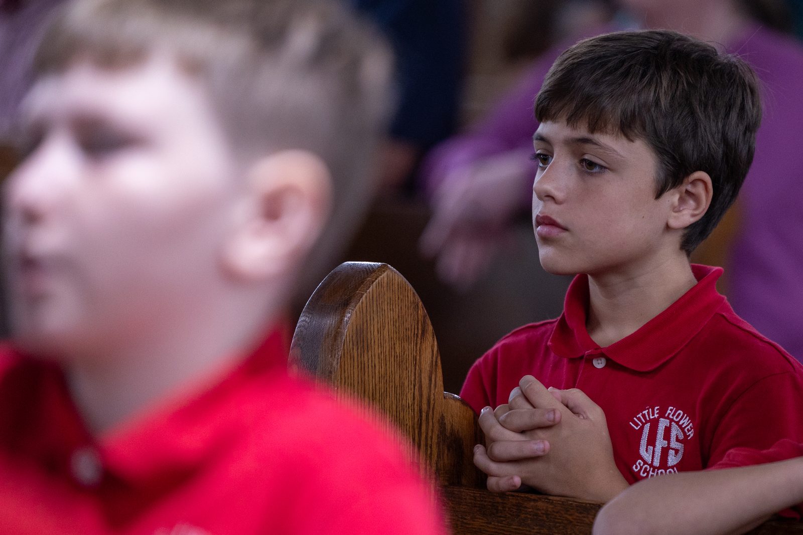At right, Kellen Holmes, a student at Little Flower School in Great Mills, Maryland, prays during a Mass on Oct. 1, 2024 at Holy Face Church in Great Mills for the feast day of the school’s patron saint, St. Thérѐse of Lisieux, who is known as the Little Flower. At center in the photo below, Little Flower student Drake Gordon prays during the Mass. (Catholic Standard photos by Mihoko Owada)