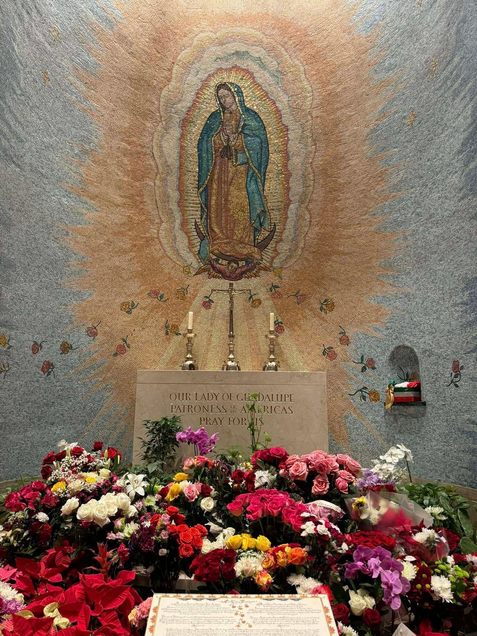 Prolijo arreglo floral, donado por la feligresa mexicana Minerva Jiménez, yace al pie de la imagen de Nuestra Señora de Guadalupe, Reina de las Américas.