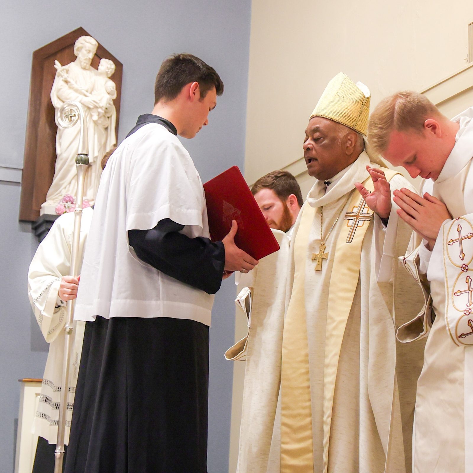 Washington Cardinal Wilton Gregory offers the closing prayer at a June 5, 2024 Mass at St. Mary’s Ryken High School in Leonardtown, where he blessed the new altar at the school’s renovated Chapel of Charity. At right is Deacon Christopher Feist, a member of the class of 2016 at St. Mary’s Ryken. Standing on the other side of the cardinal is Deacon John Winslow from St. Mary’s Ryken’s class of 2015, who also assisted at the Mass. Deacon Feist and Deacon Winslow are among 16 men who will be ordained by Cardinal Gregory as new priests for The Roman Catholic Archdiocese of Washington on June 15 at the Basilica of the National Shrine of the Immaculate Conception. (Photo by HD Photography for St. Mary’s Ryken High School)