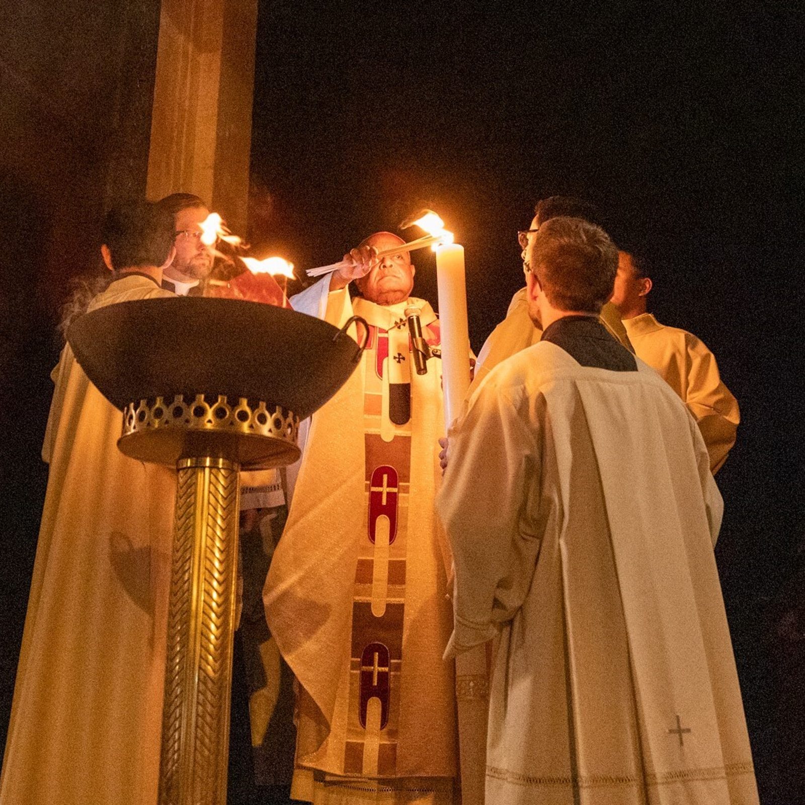 Standing outside the main entrance of the Cathedral of St. Matthew the Apostle in Washington, D.C., at the start of the March 30, 2024 Easter Vigil there, Cardinal Wilton Gregory lights the Paschal Candle from the Easter flame. (Catholic Standard photo by Mihoko Owada)