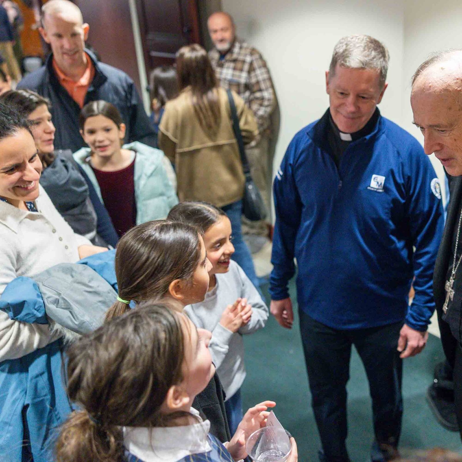 After celebrating a Mass on Feb. 11 marking the 100th anniversary of Our Lady of Lourdes Parish in Bethesda, Washington Cardinal Robert W. McElroy, joined by Father Rob Walsh, the parish’s pastor, talks with Keira Anderson and Teresita and Catalina Tapia-Briot, who are students at Our Lady of Lourdes School. (Catholic Standard photo by Mihoko Owada)