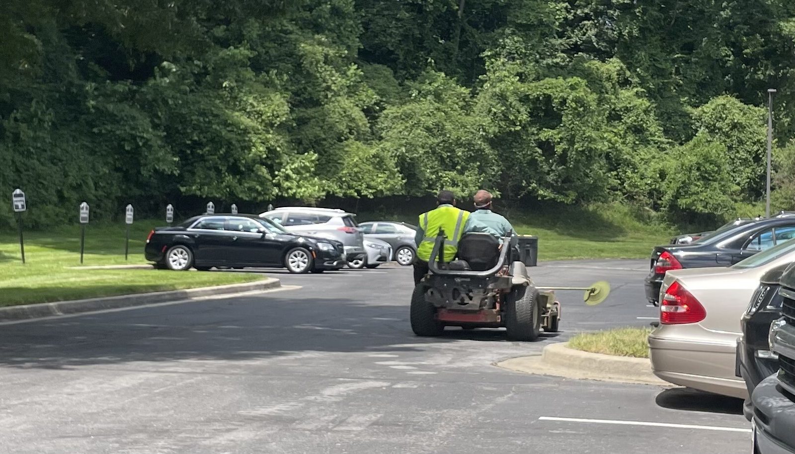El venezolano Gabriel Rondón, en compañía de un asistente, conduce una máquina para cortar grama.
