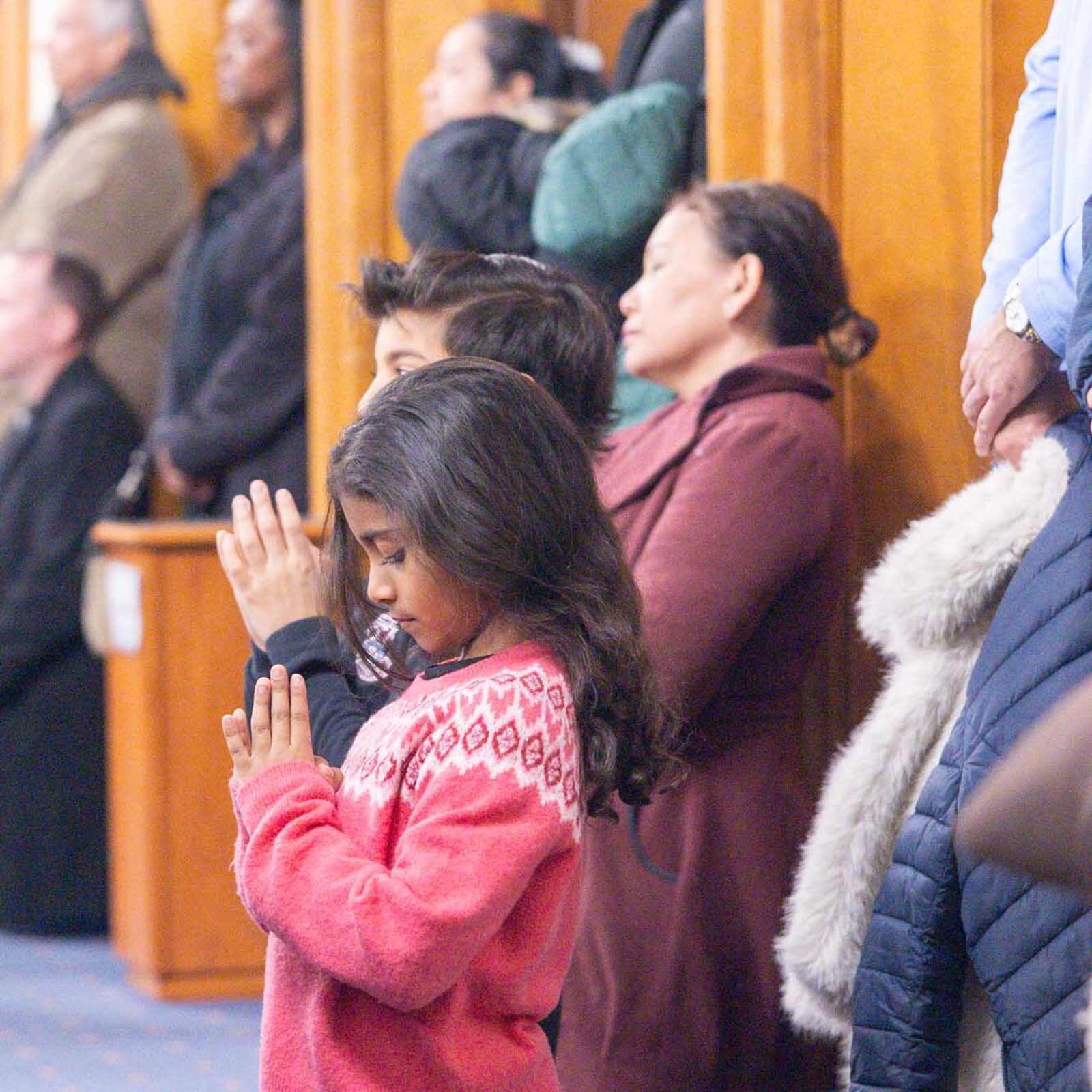 Siblings Devassy and Kavira Thomas, who are students at Our Lady of Lourdes School in Bethesda, kneel in prayer during a Feb. 11 Mass at the church commemorating the parish’s 100th anniversary. (Catholic Standard photo by Mihoko Owada)