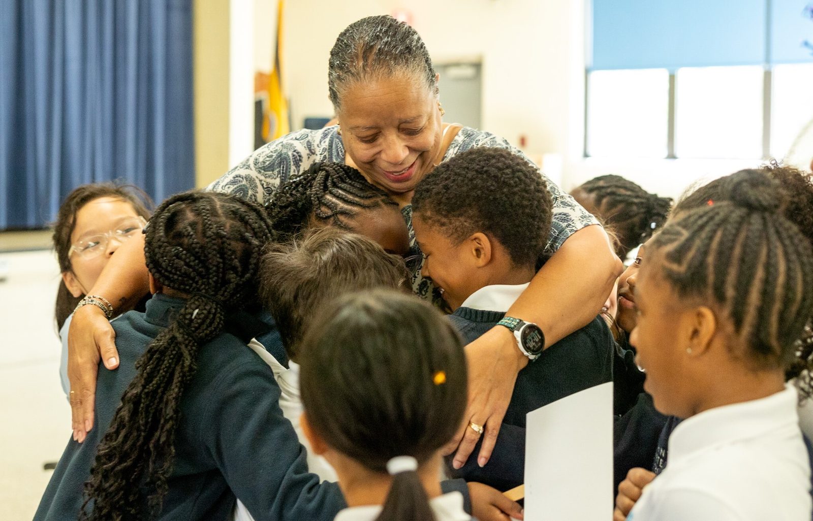 Margo VanDenBossche, a third grade teacher at Saint Peter’s School in Waldorf, Maryland, has a group hug with her students after it was announced on April 15 that she is a 2024 Golden Apple Award winning teacher. (Catholic Standard photo by Mihoko Owada)