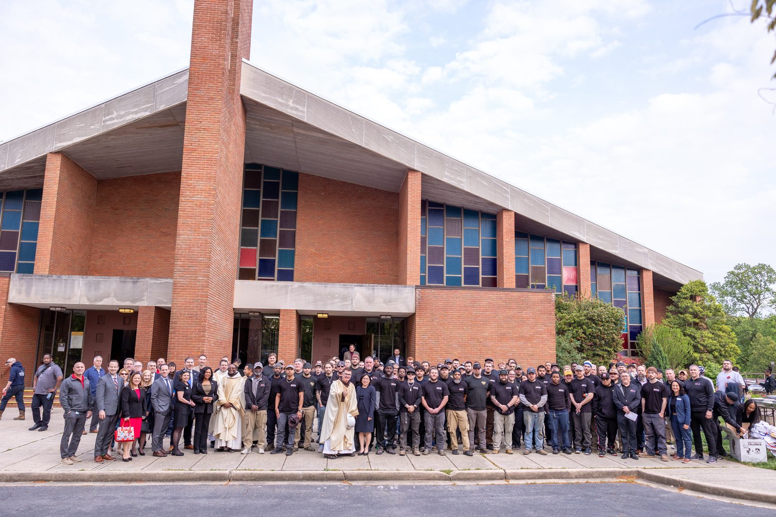 The hundreds of union workers who attended the fourth annual Building Trades’ Workers Memorial Mass on April 25, 2024 at St. Camillus Church in Silver Spring, Maryland, stand together outside the church after the Mass. At front center are Franciscan Father Brian Jordan, the pastor of St. Camillus who was the main celebrant and homilist at the Mass, and Portia Wu, the Secretary of Labor for the State of Maryland who spoke after Communion. (Catholic Standard photo by Mihoko Owada)