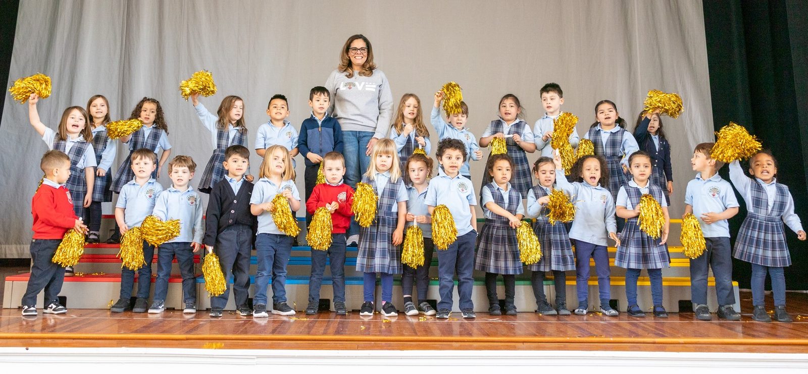 After learning that she is a 2024 Golden Apple Award-winning teacher in The Roman Catholic Archdiocese of Washington, Patricia Gonzalez, who teaches pre-kindergarten to 3-year-old students at Sacred Heart School in Washington, D.C., and is the department head for Early Childhood Education there, poses for a photo with her students. (Catholic Standard photo by Mihoko Owada)