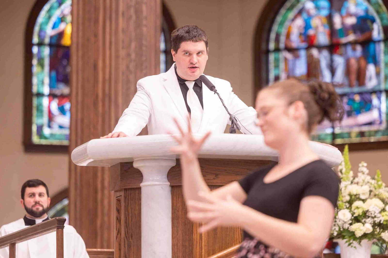 Timmy Menard of St. Aloysius Parish in Leonardtown serves as a cantor during the White Mass on Oct. 26 at Our Lady of Mercy Church in Potomac. In the foreground, Erin Schneider serves as an American Sign Language interpreter during the Mass. (Catholic Standard photo by Mihoko Owada)