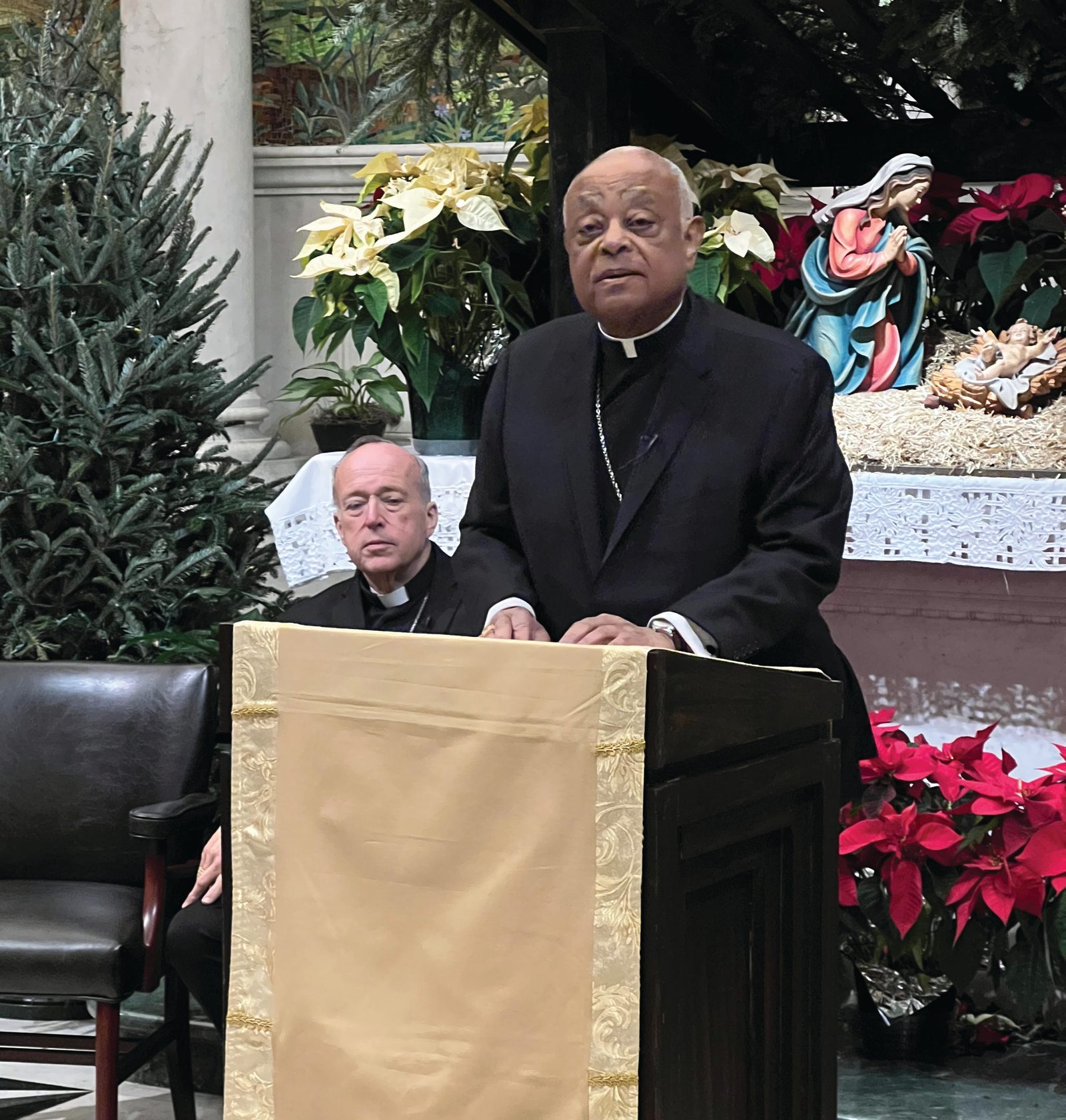Cardinal Wilton Gregory speaks at a Jan. 6, 2025 press conference at the Cathedral of St. Matthew the Apostle in Washington, D.C. Cardinal Robert McElroy is seated behind him. That morning, Pope Francis named Cardinal McElroy, the bishop of the Diocese of San Diego, as the new archbishop of Washington, succeeding Cardinal Gregory, who served in that role since 2019. On Jan. 6, Pope Francis also accepted the resignation of Cardinal Gregory as the archbishop of Washington. As required by Church law, Cardinal Gregory had submitted his resignation to the pope two years ago after he turned 75 on Dec. 7, 2022. (Photo by Geoffrey Ros/The Roman Catholic Archdiocese of Washington)