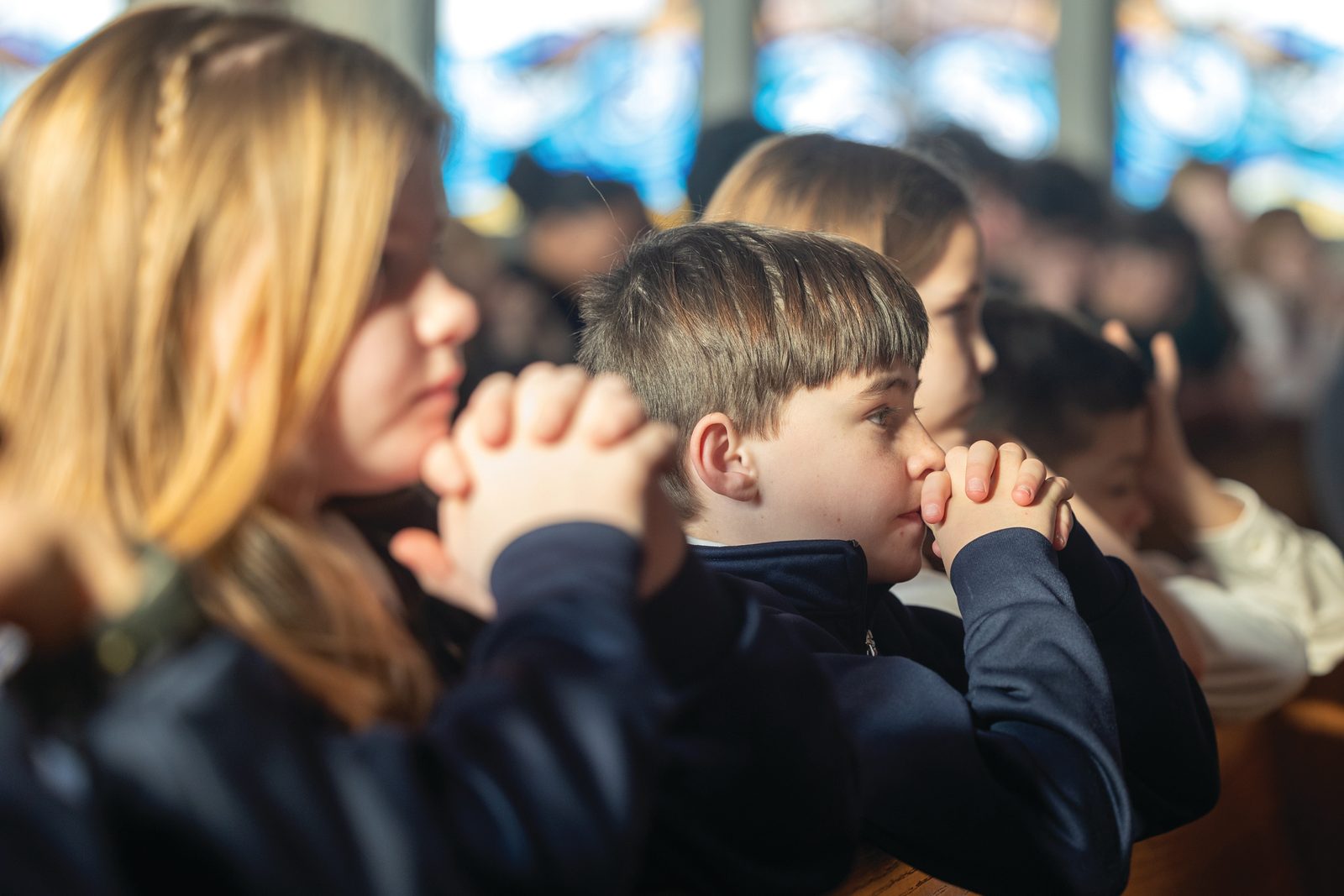Fourth graders Hallie Clarke (at left) and Jacob Potter (at center) of St. Mary’s School in Bryantown, Maryland, pray during a Catholic Schools Week Mass on Jan. 28, 2025 at St. Peter’s Church in Waldorf for students in Charles County Catholic schools. (Catholic Standard photo by Mihoko Owada)