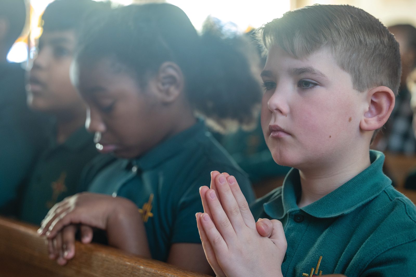 Fourth graders Lincoln Adams (at right) and Navneet Singh (at center) from Archbishop Neale School in La Plata, Maryland, pray during a Catholic Schools Week Mass on Jan. 28, 2025 at St. Peter’s Church in Waldorf for students in Charles County Catholic schools. (Catholic Standard photo by Mihoko Owada)